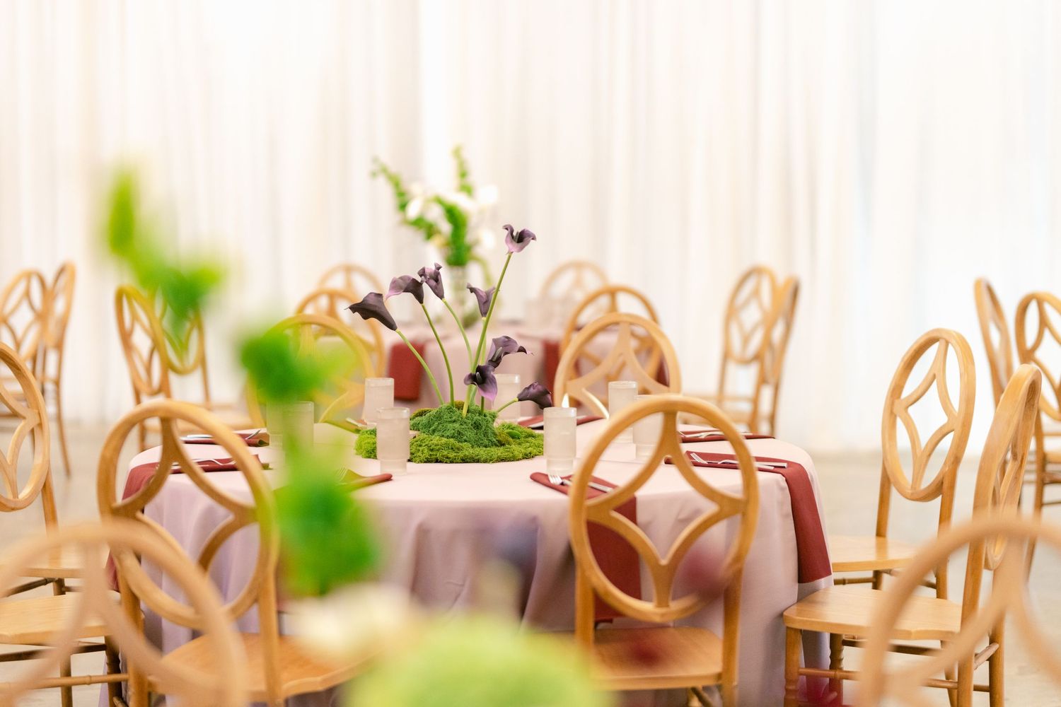 Elegant wedding reception table setup with ornate gold chairs and floral centerpieces in a bright indoor venue.