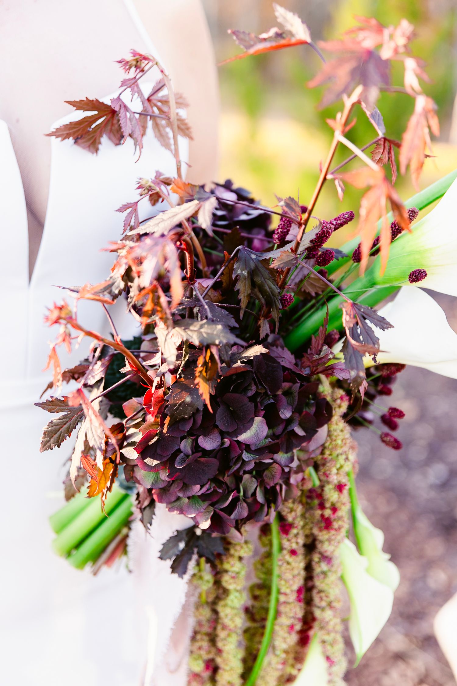 Close-up of a moody fall bouquet featuring dark purple flowers and Japanese maple leaves.