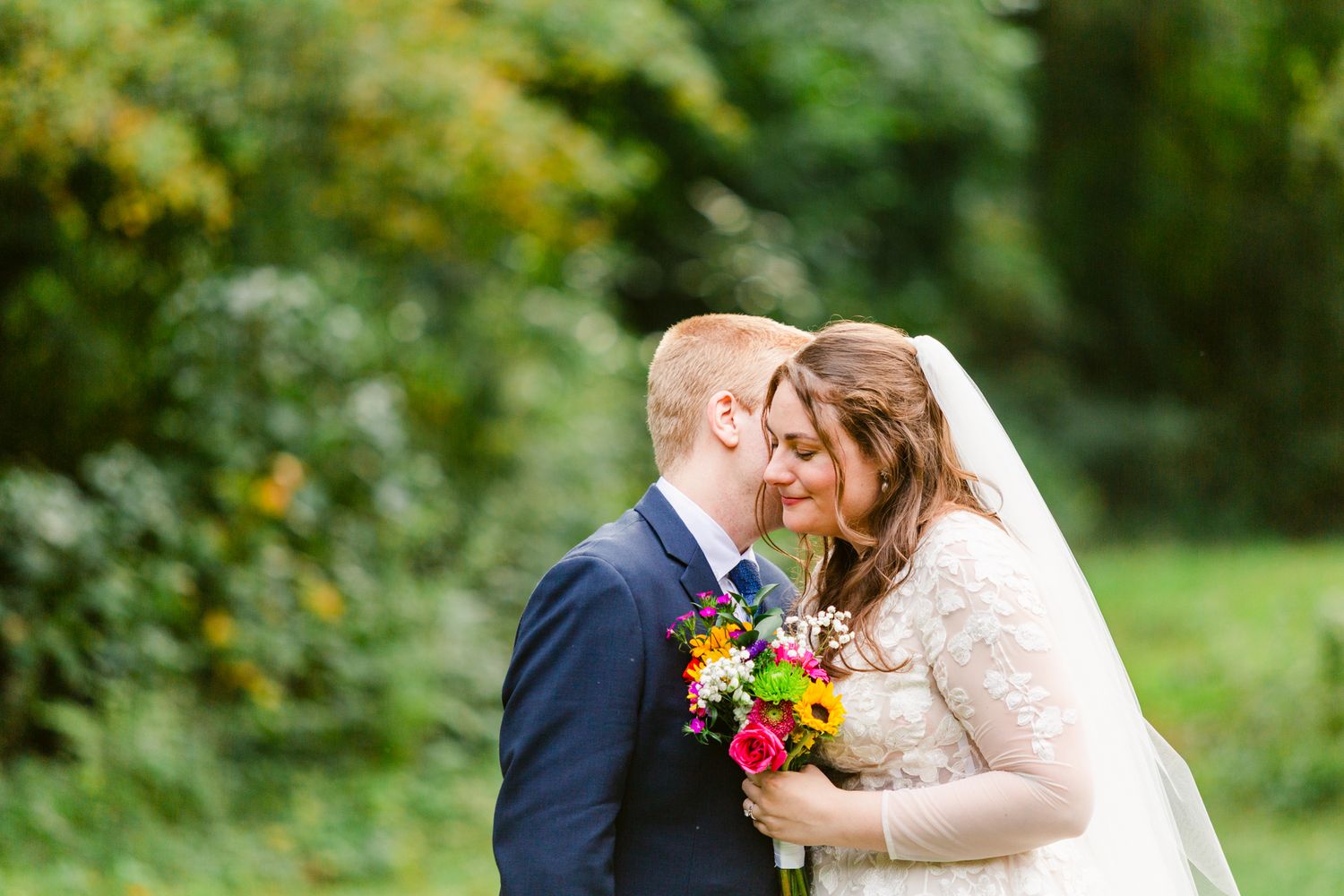 A couple shares a tender kiss in a lush garden setting during their wedding celebration.