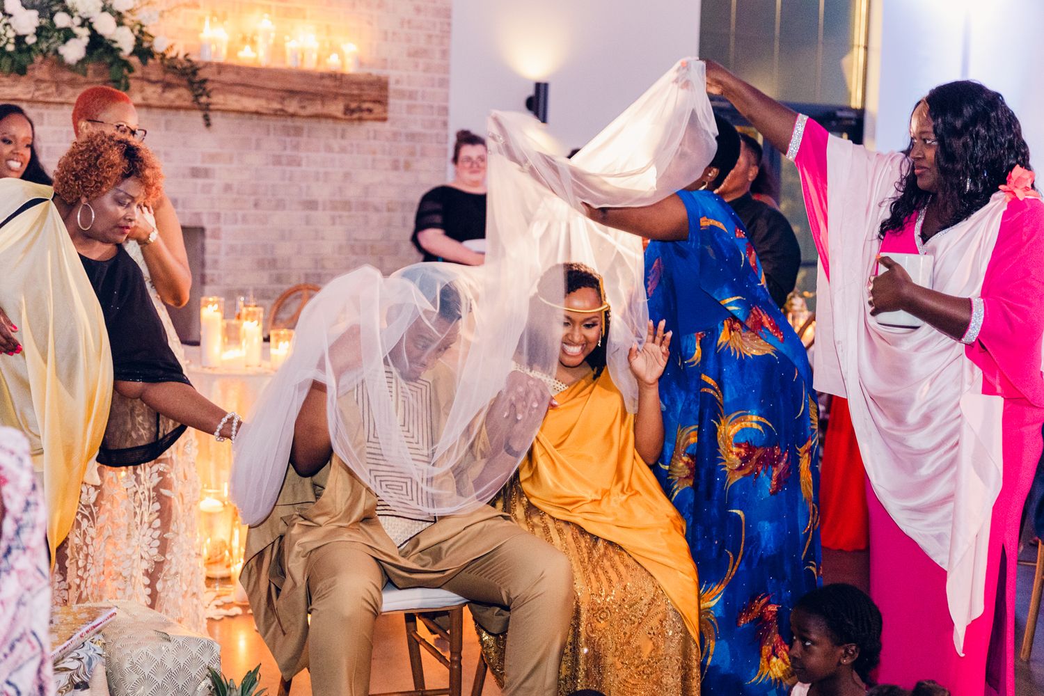Wedding party members in yellow and blue attire dancing and celebrating at an indoor reception.