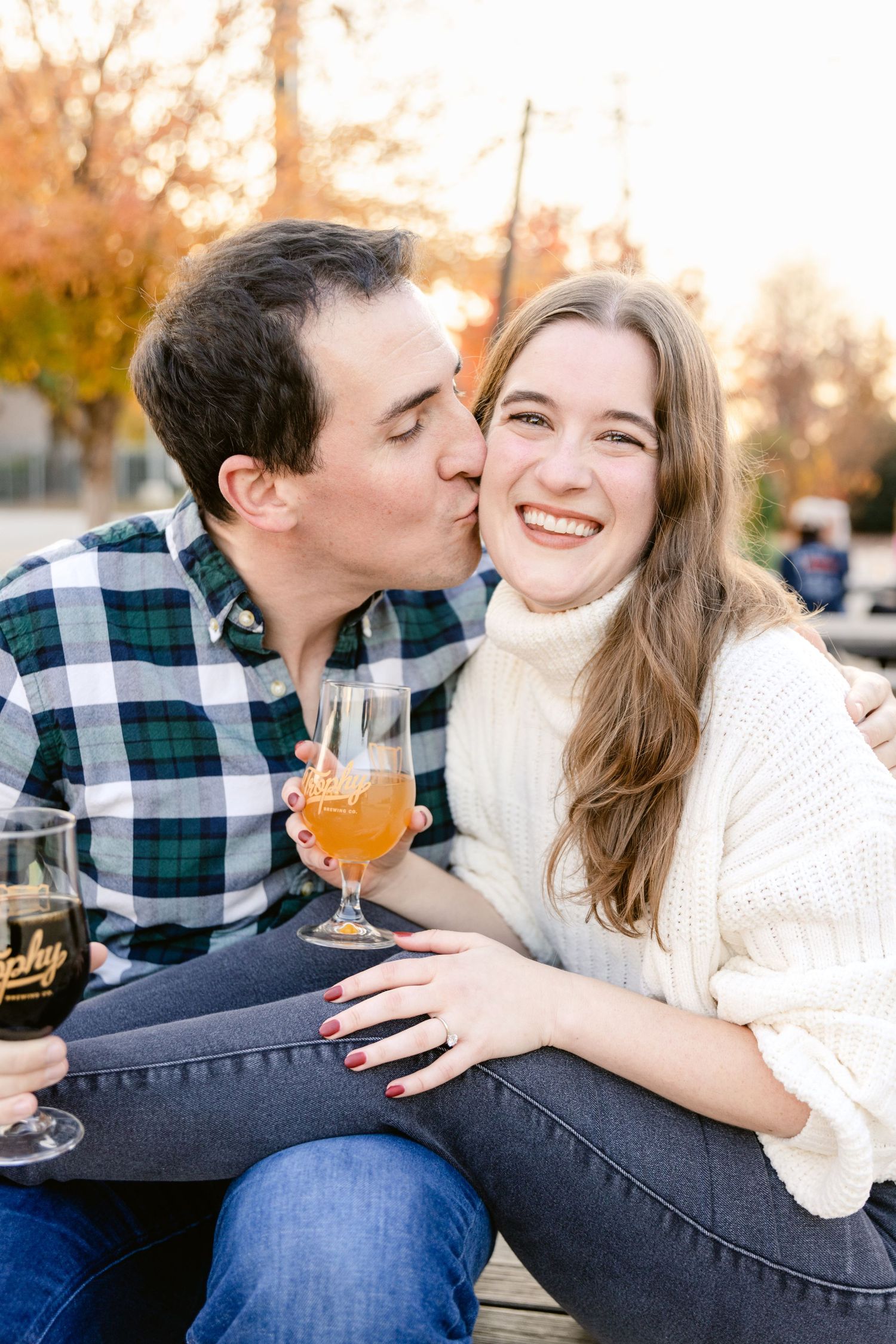 A tender autumn moment shared over drinks outdoors at sunset, with cozy sweaters and warm smiles.