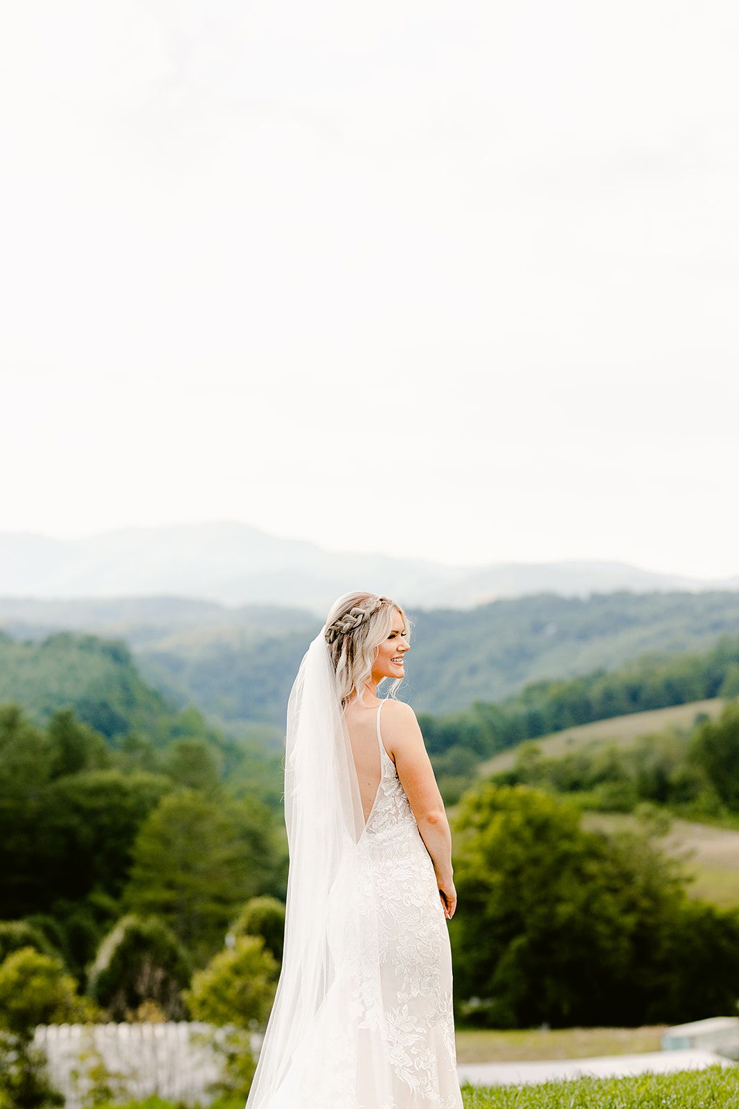 Scenic mountaintop bridal portrait featuring flowing veil and fitted lace gown.