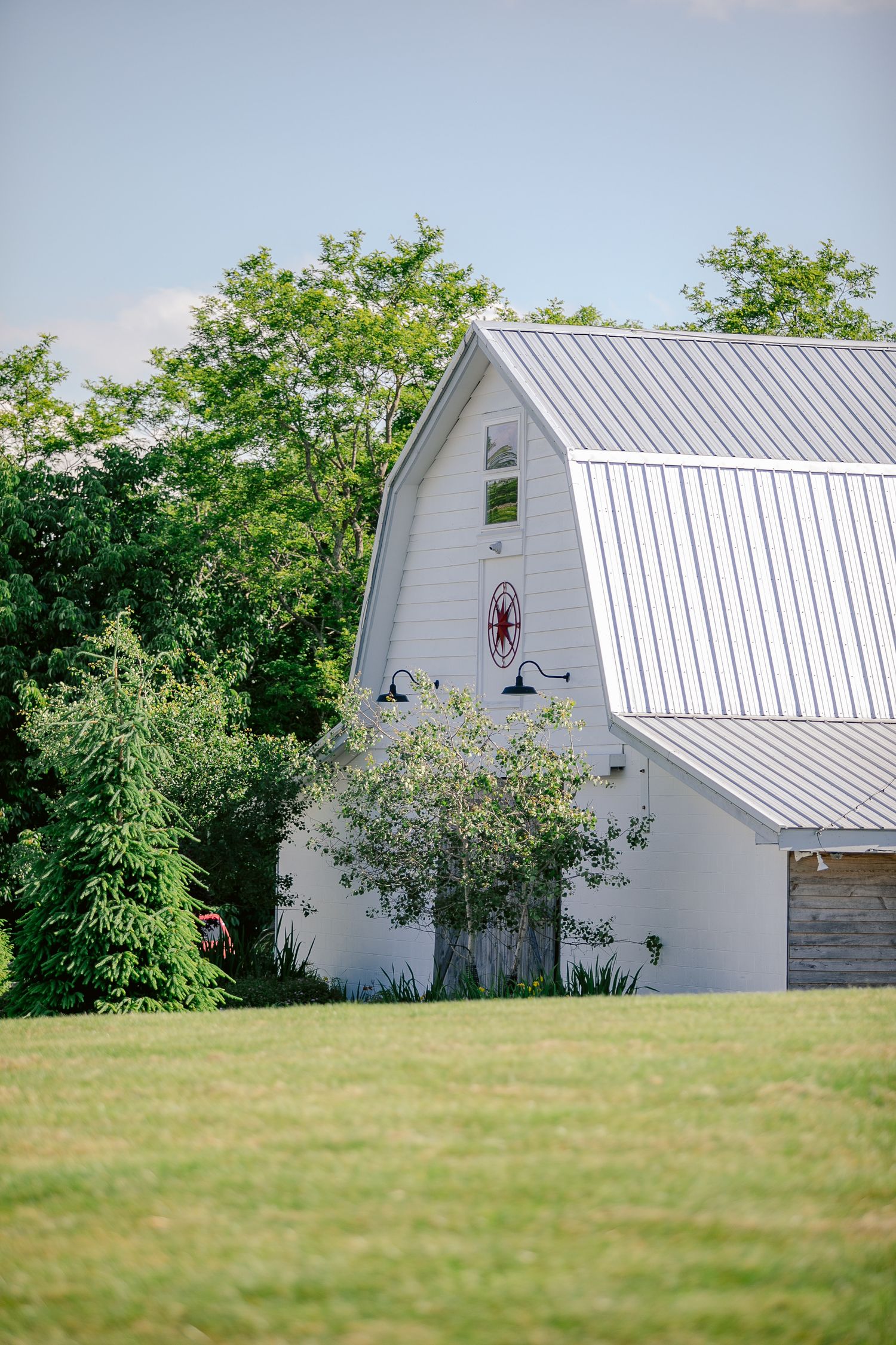 White barn-style building with metal roof and decorative elements on a green lawn.