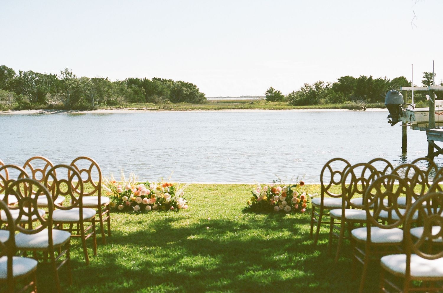 Outdoor wedding ceremony setup with wooden chairs overlooking a waterfront view.
