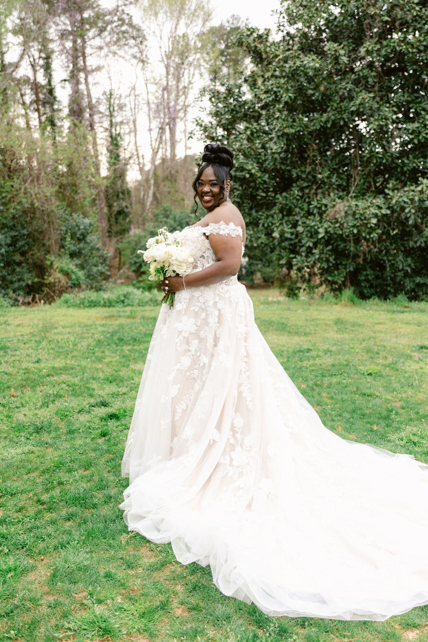 A stunning bridal portrait session in a lush garden setting showcasing an elegant white wedding gown with flowing train.