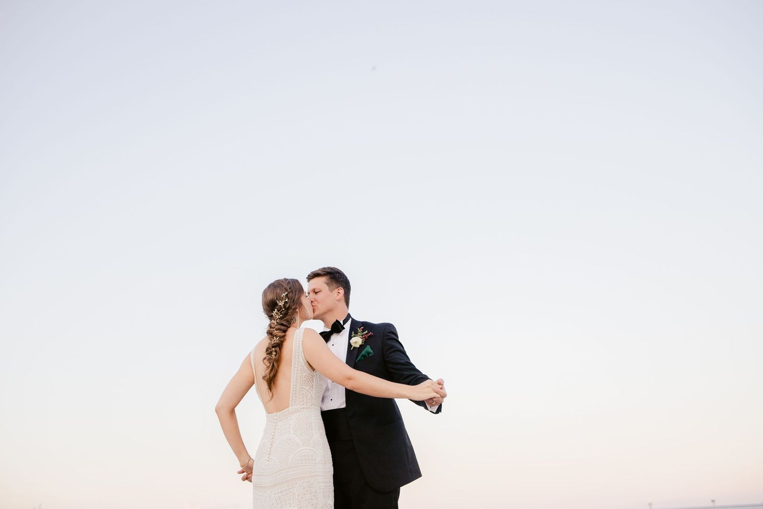 Joyful couple dancing outdoors during their wedding celebration at sunset.