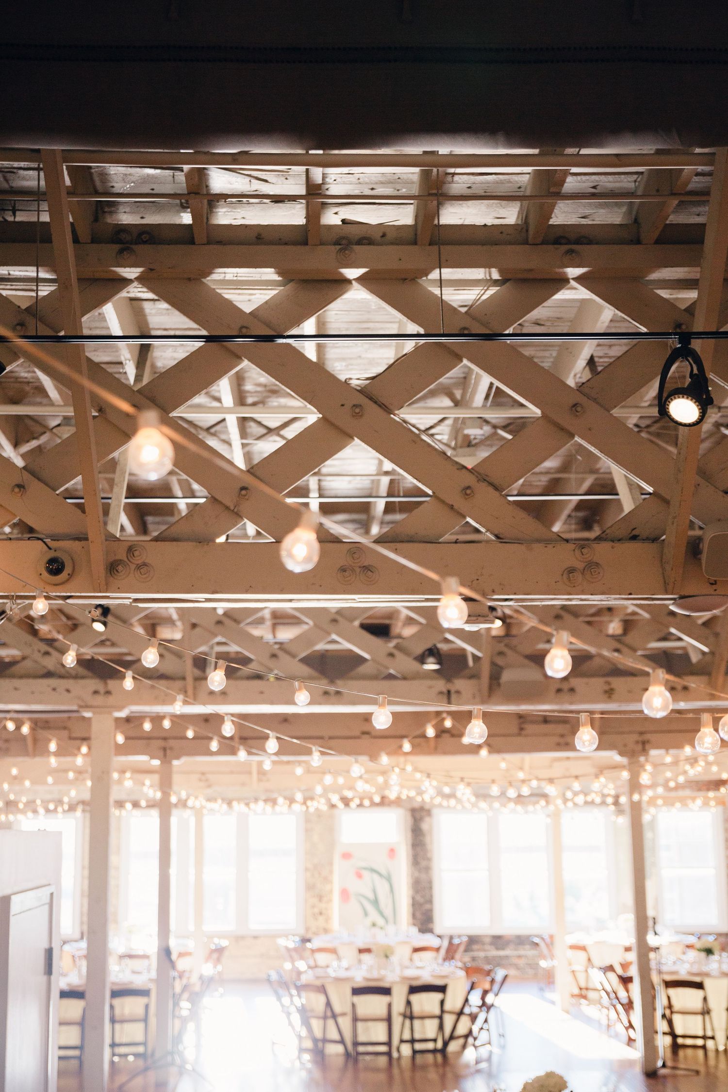 Industrial ceiling with lattice framework and hanging string lights creating romantic ambiance.