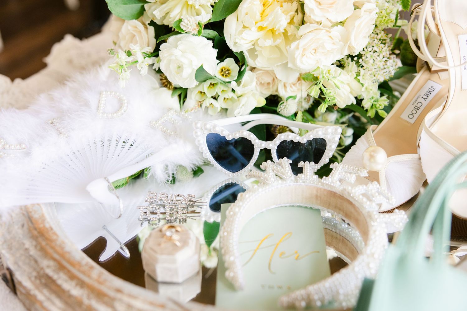 Wedding accessories including white sunglasses, floral bouquet and delicate lace details in soft pastel colors.
