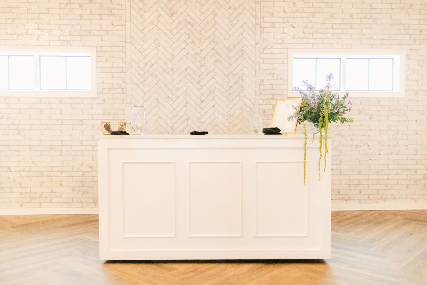 Minimalist white sideboard cabinet with herringbone pattern wall in a modern interior design setting.