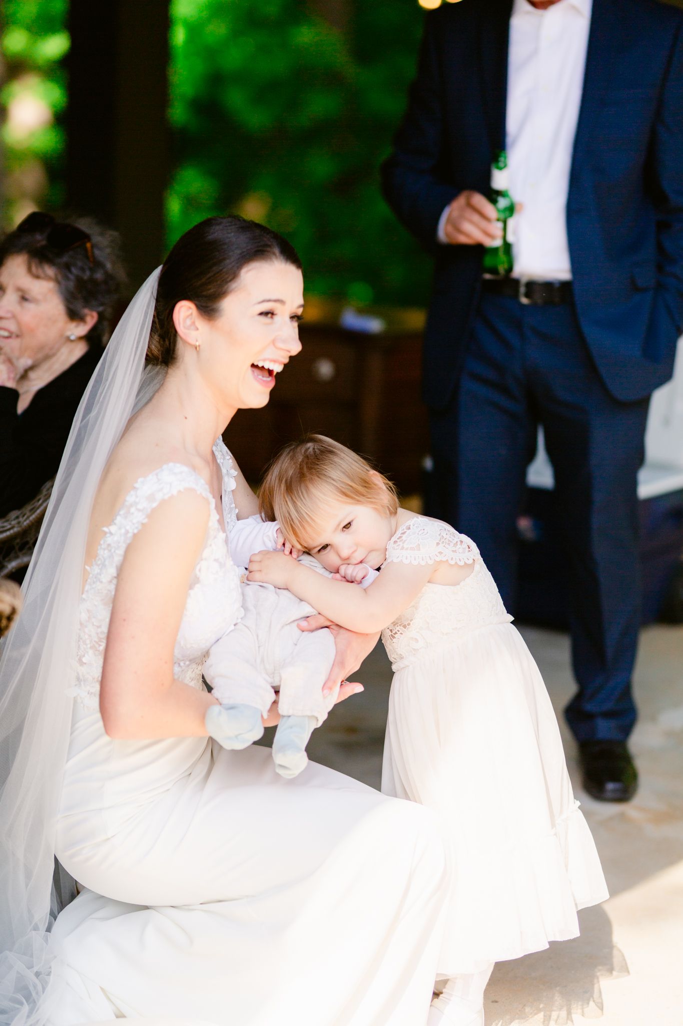Joyful moments captured at an elegant outdoor wedding celebration with bride and child in white attire.