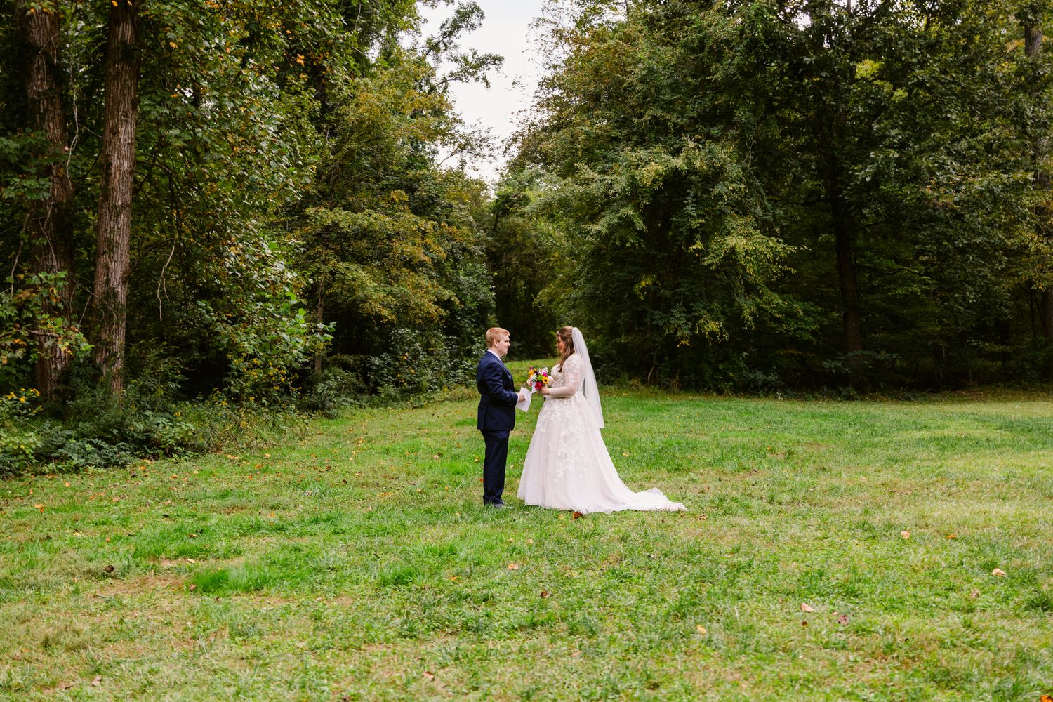 A couple shares a romantic moment in a lush green garden setting during their wedding celebration.