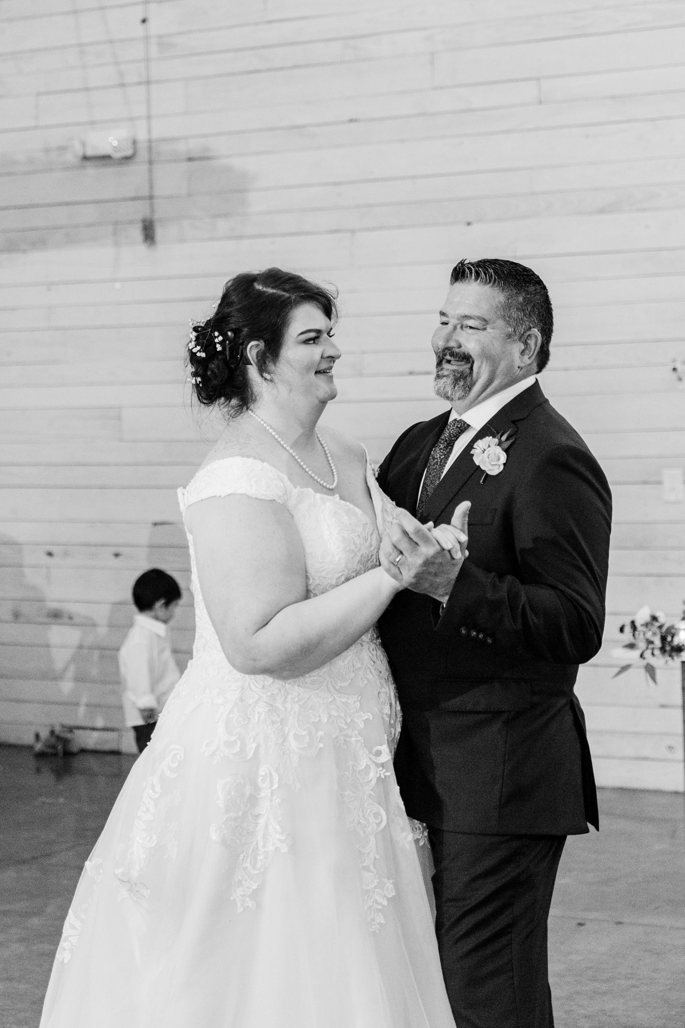 A happy couple shares their first dance at their wedding reception in a rustic barn venue.