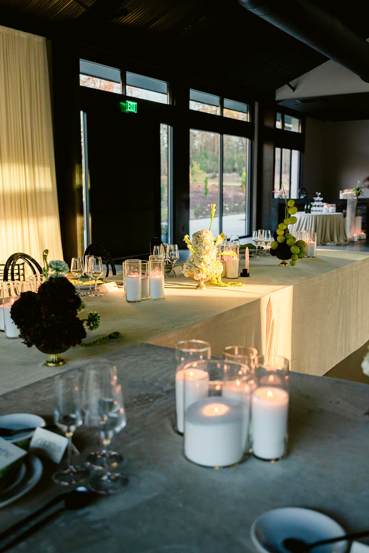 Modern event space with floor-to-ceiling windows and elegant table settings bathed in natural light.