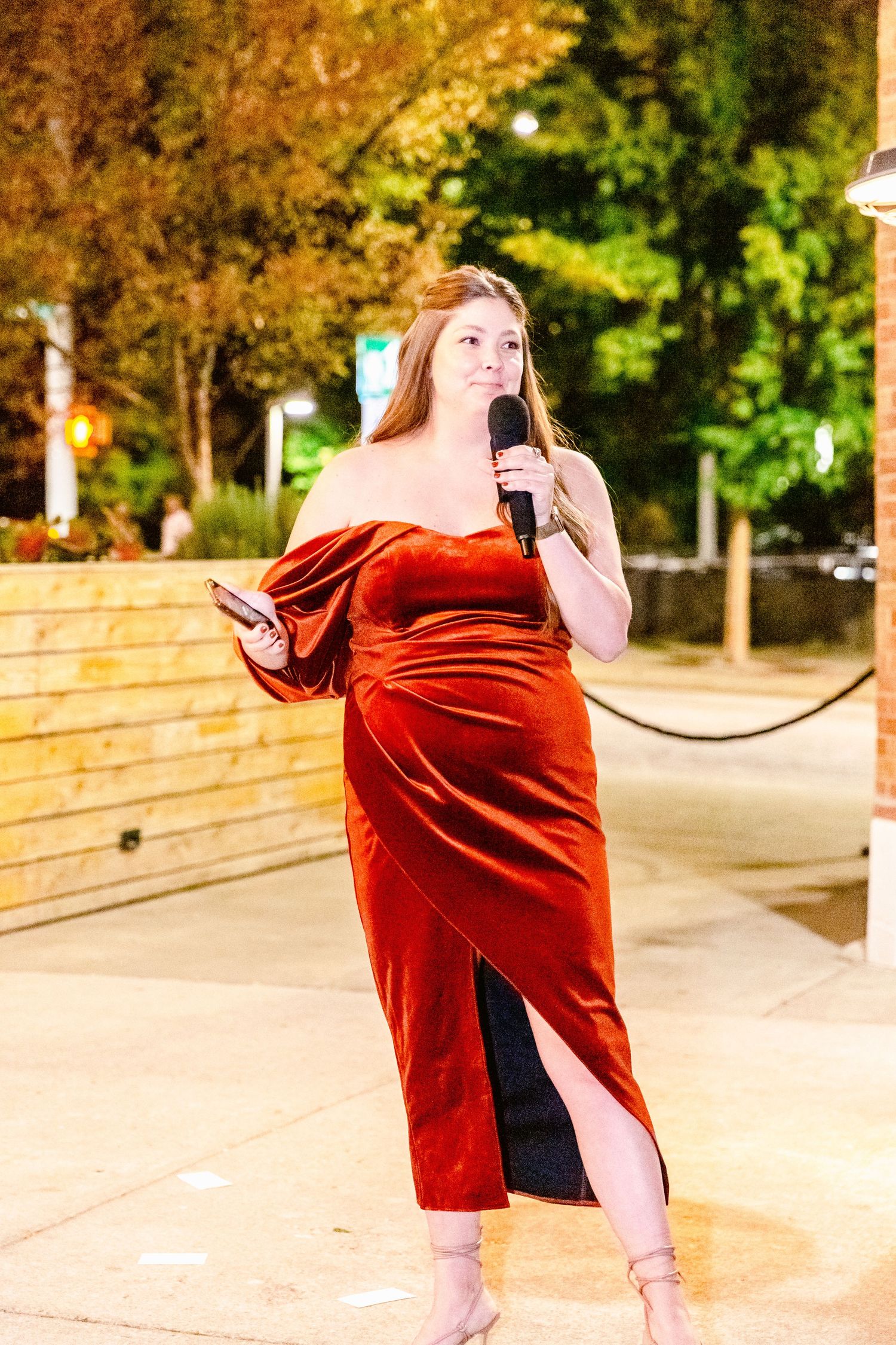 A dancer in a flowing red velvet dress performs an expressive movement sequence outdoors at dusk.