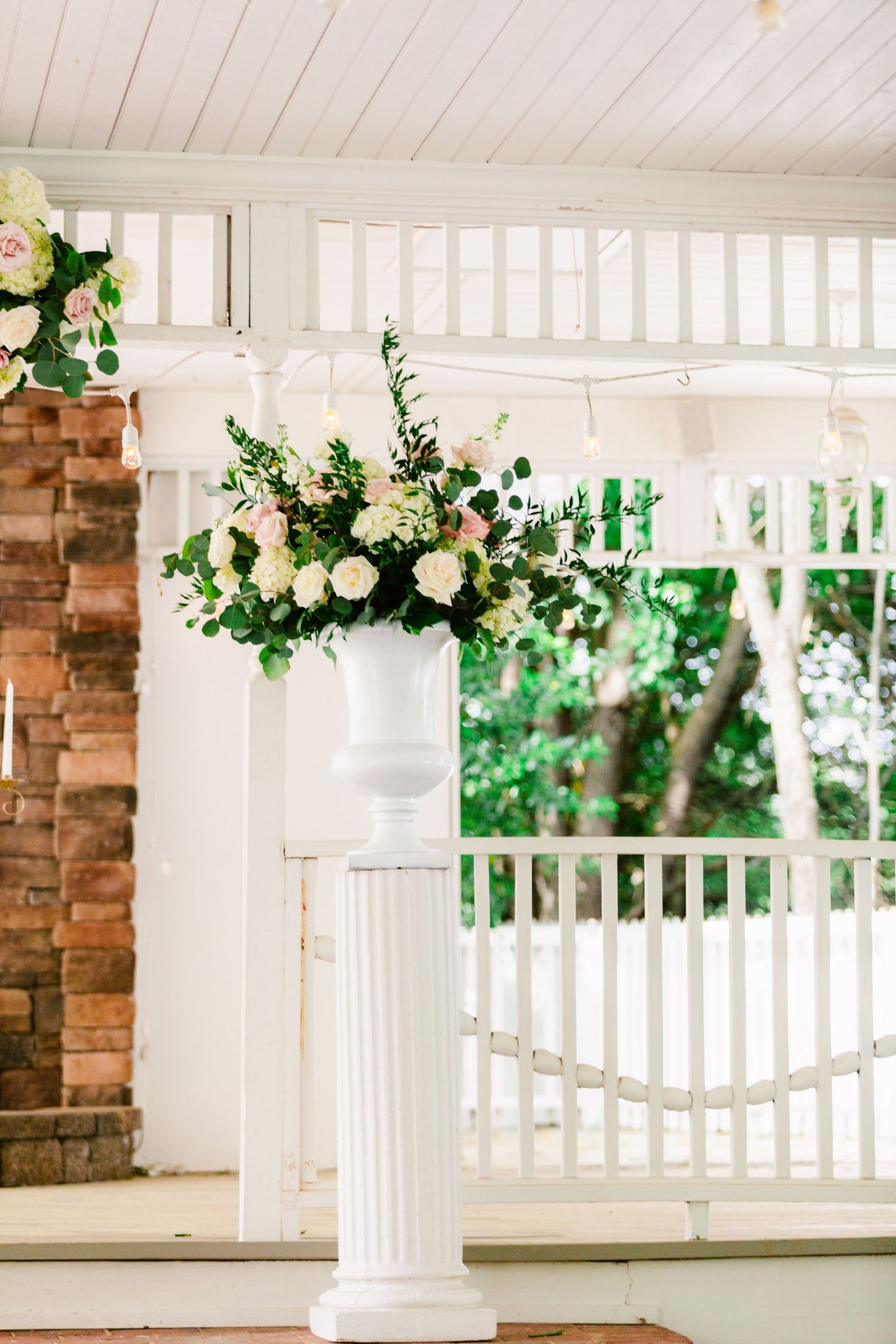 White pergola decorated with lush greenery and floral garlands for an outdoor event.