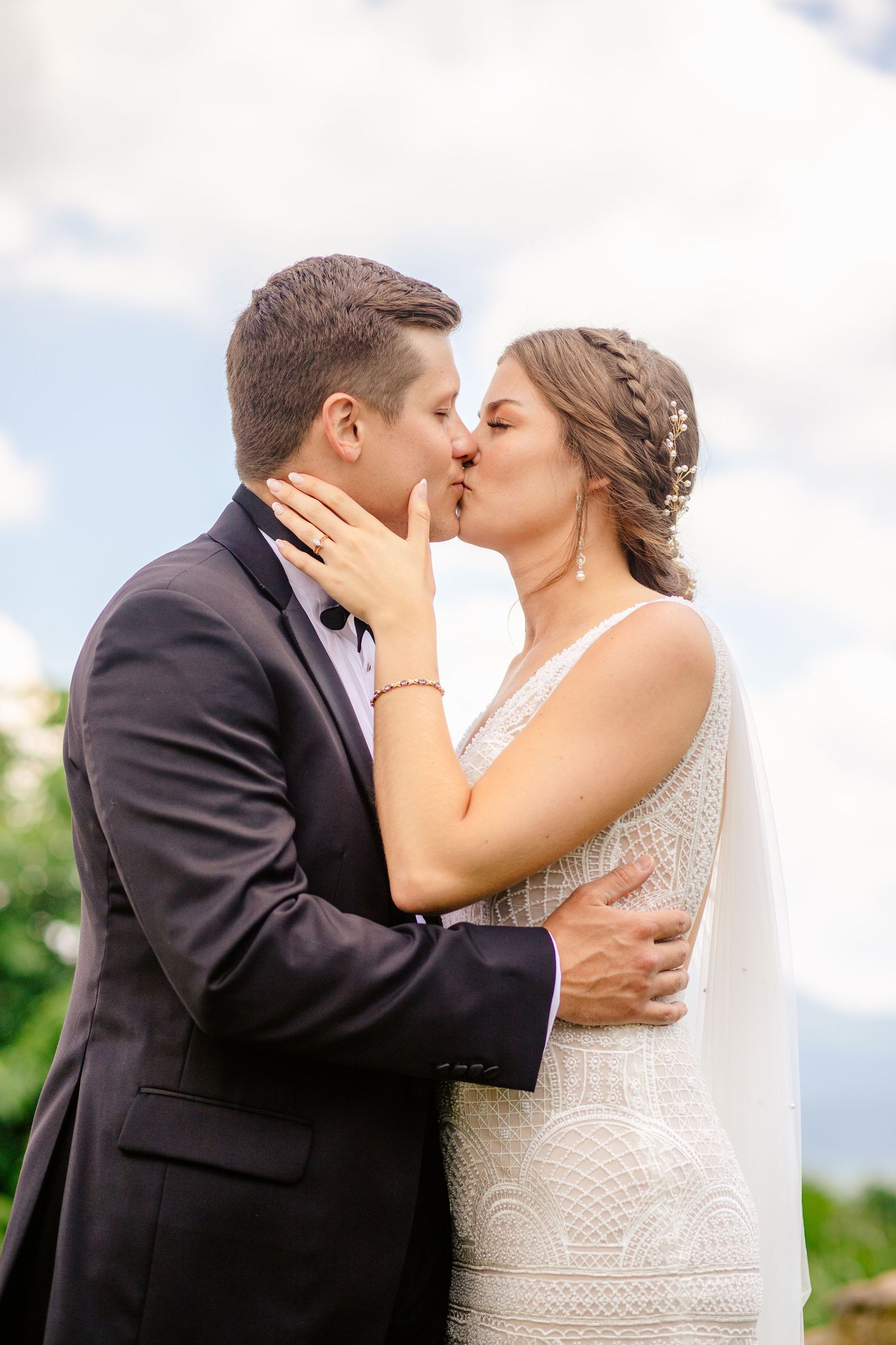 Tender wedding moment captured as couple shares passionate kiss outdoors.