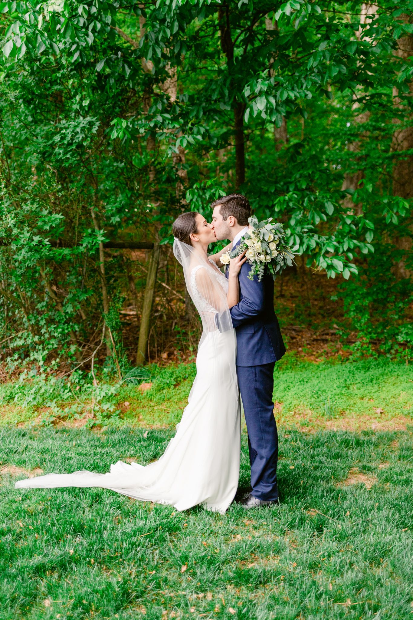 A couple dancing together in a romantic sequence on a grassy lawn surrounded by lush green trees.