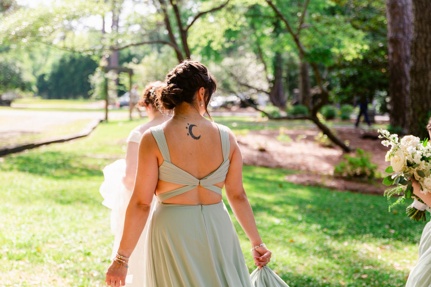 Wedding couple walking hand in hand through a lush garden setting on a sunny afternoon.