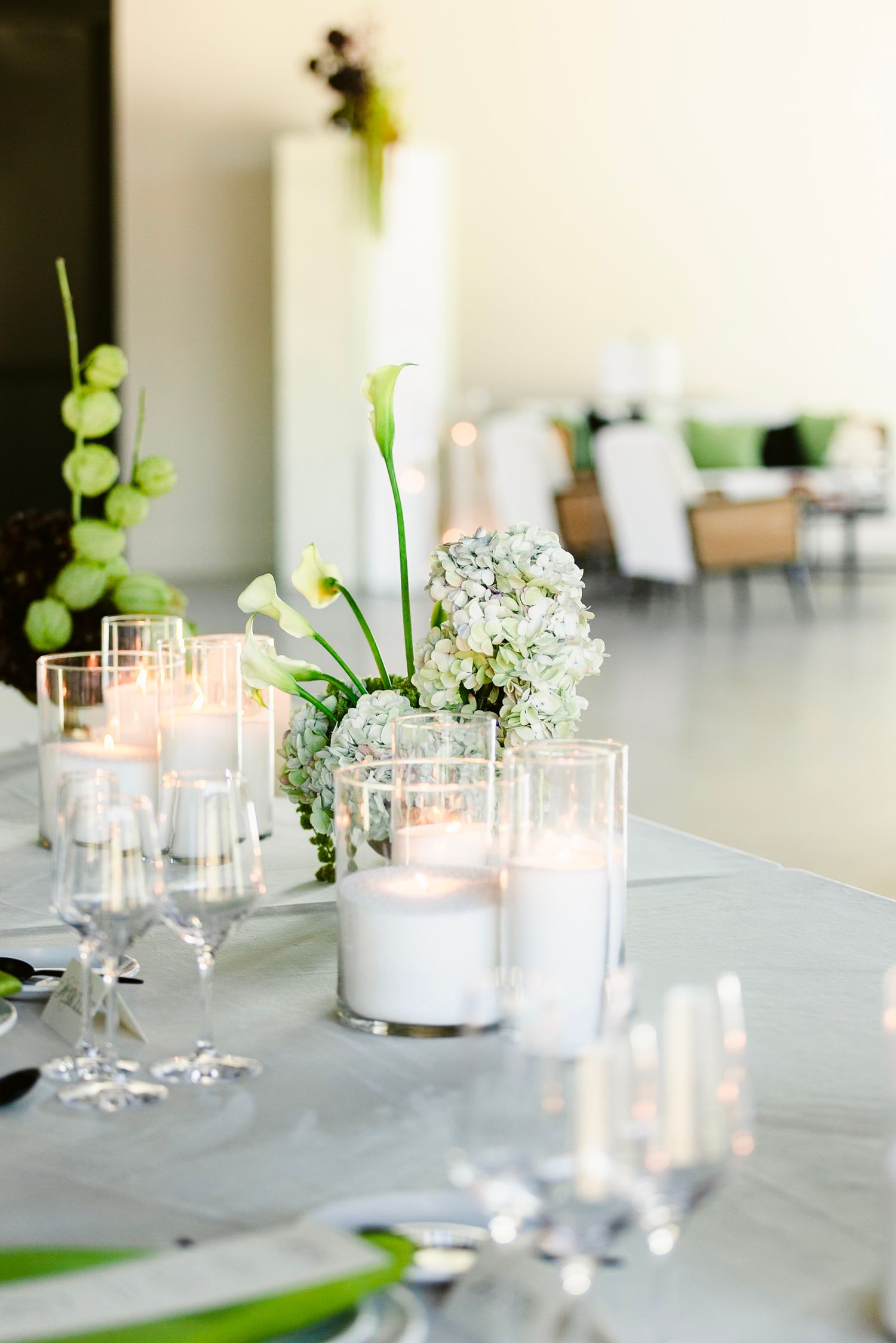 Wedding reception table setting with white candles, delicate floral arrangements, and crystal glassware.