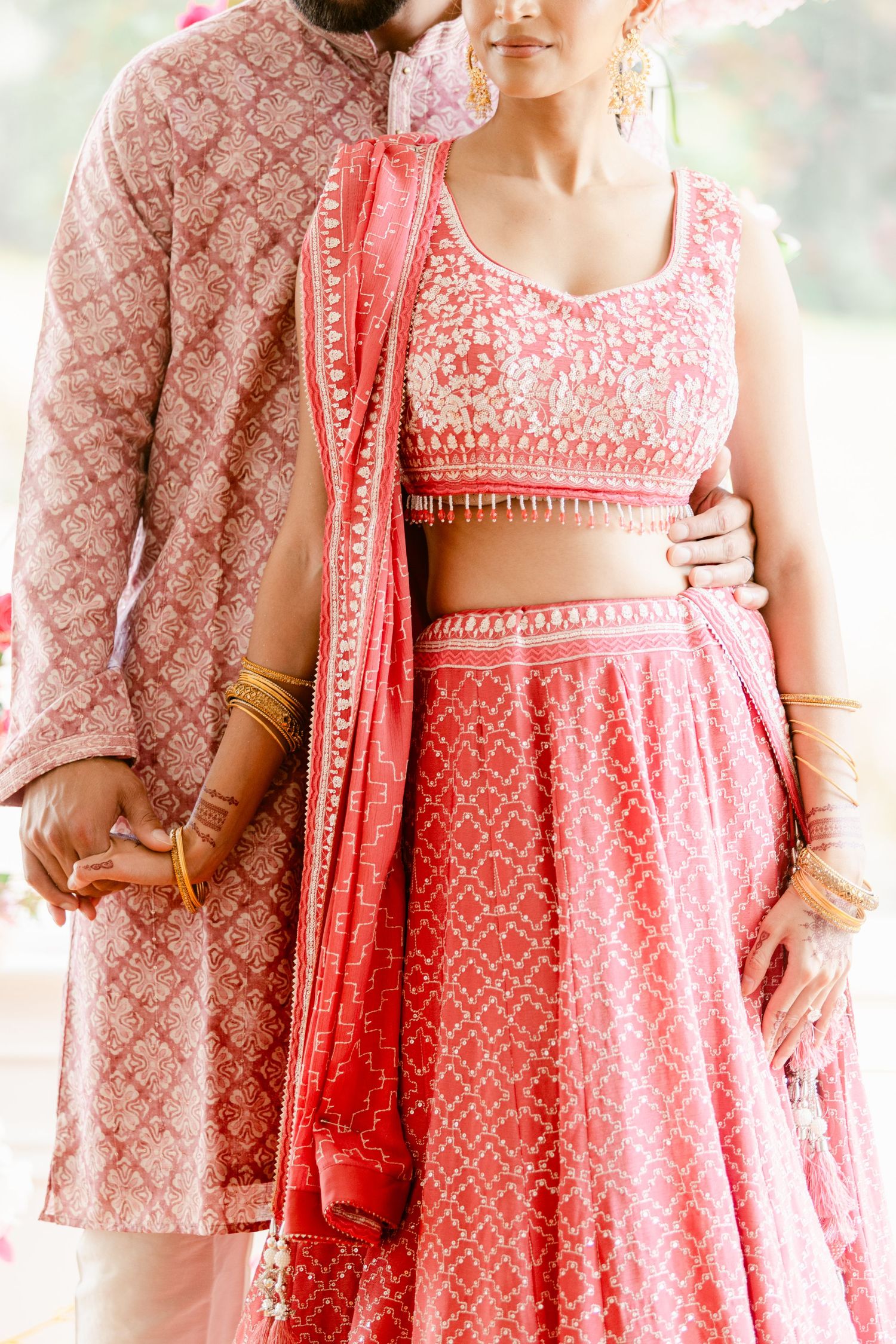 Close-up of coral and pink patterned traditional Indian dresses with detailed embroidery.