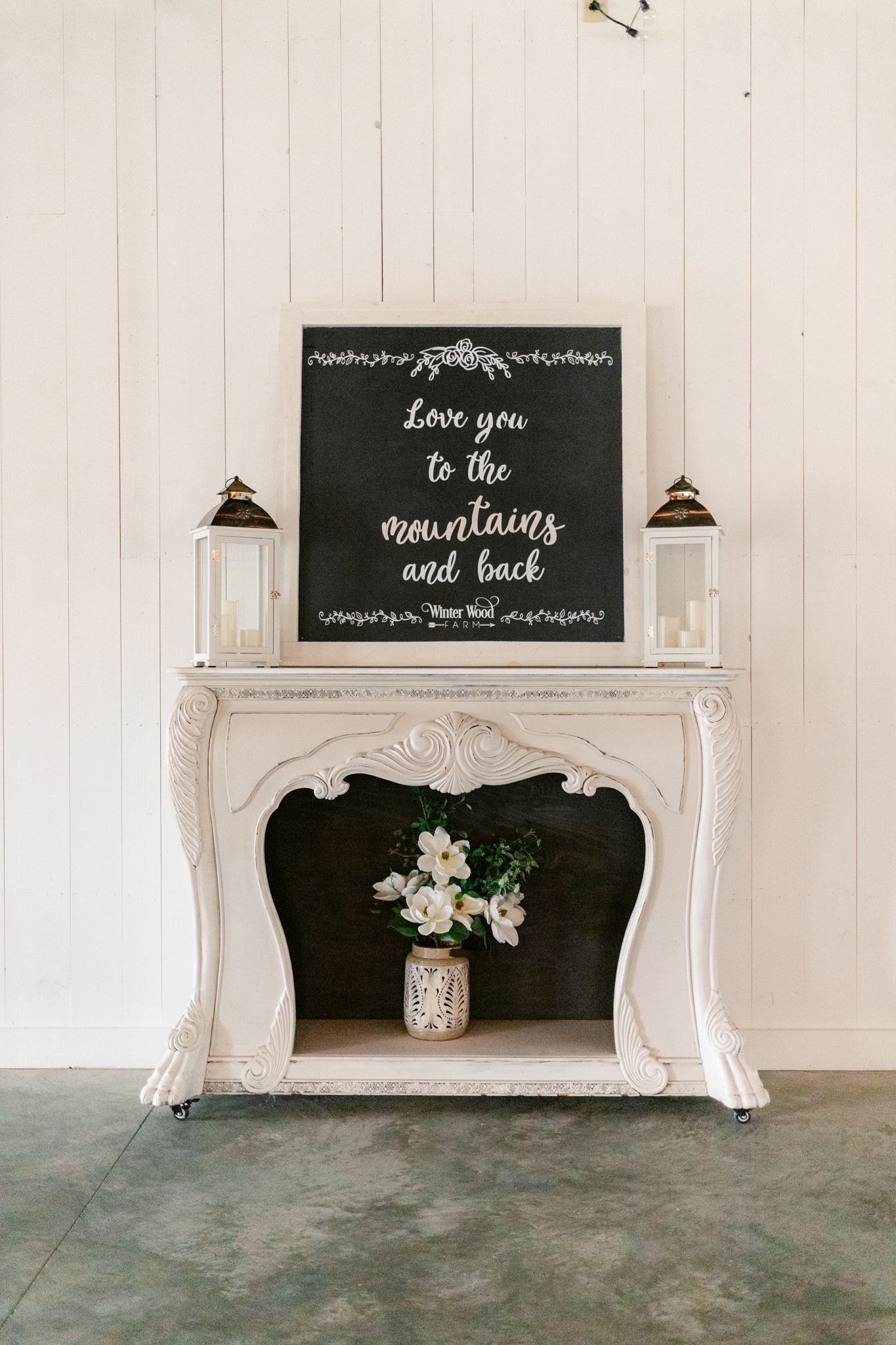 Elegant white vintage mantels with chalkboard signs and floral arrangements in a rustic white room.