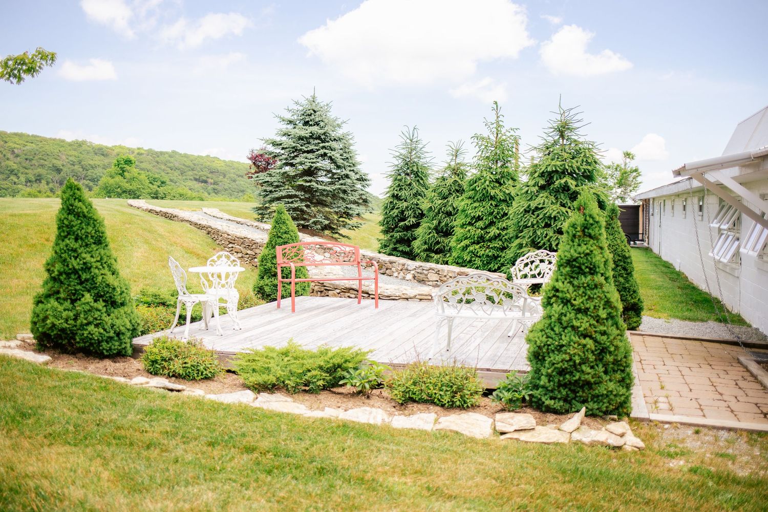 Landscaped garden venue with evergreen trees and stone pathway leading to patio area.