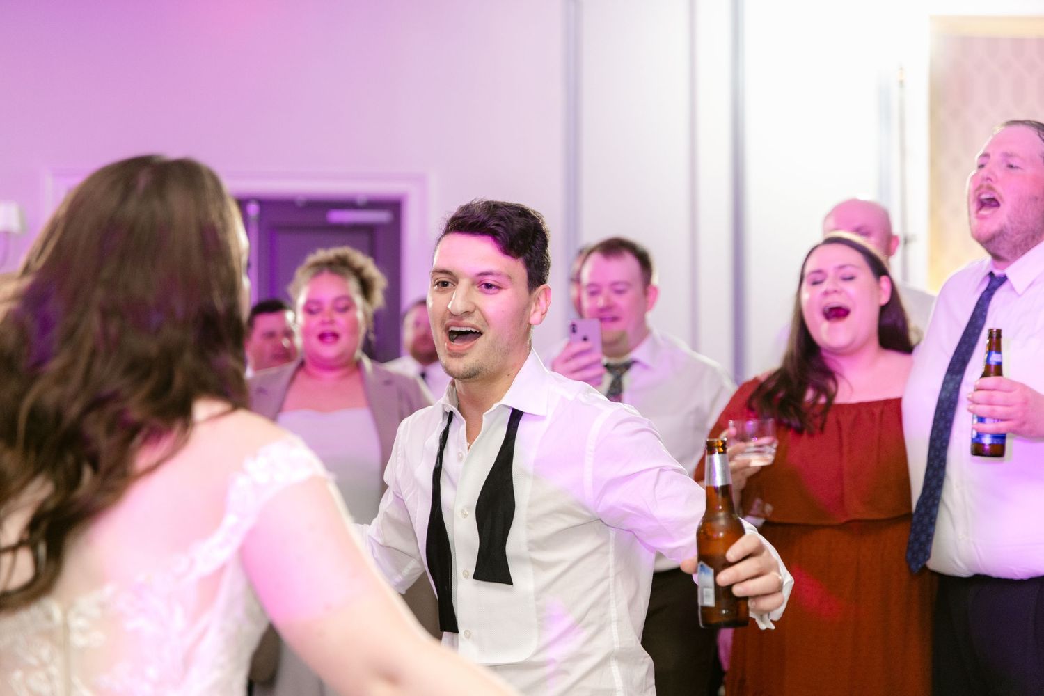 A series of candid wedding reception photos showing guests laughing and dancing in a joyful celebration atmosphere.