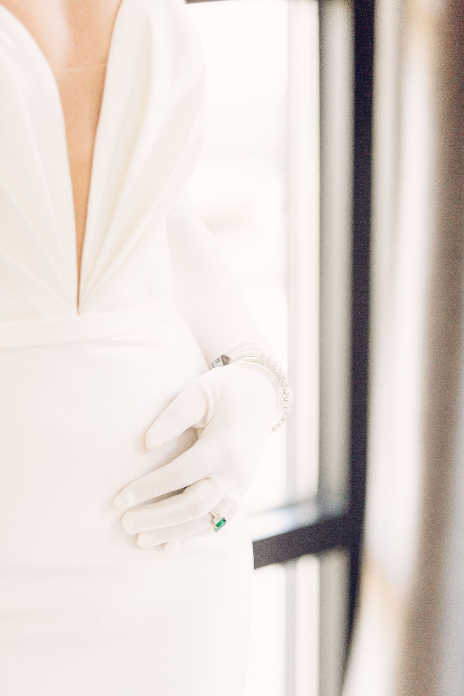 White wedding dress hanging against a bright window in natural light.