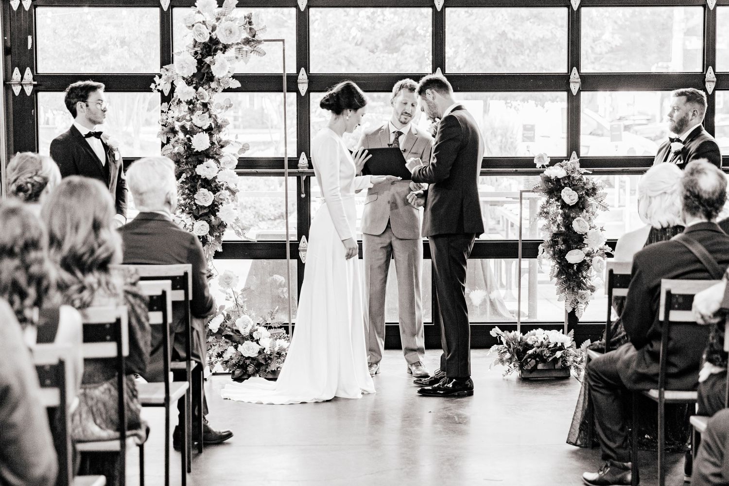 A wedding ceremony in progress with guests seated in rows watching the couple exchange vows at the altar.
