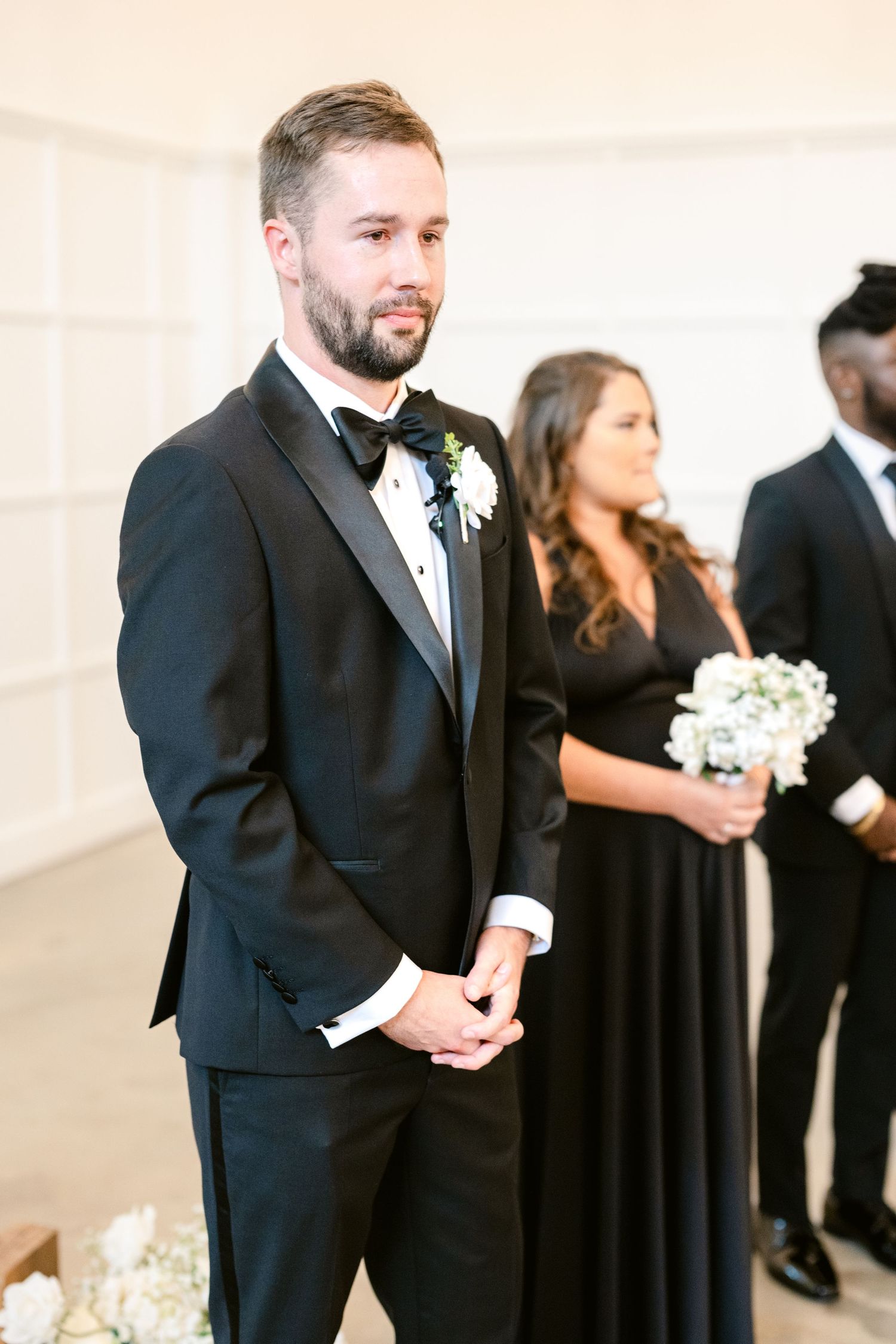 Wedding party members in formal black attire walk together during a ceremony procession.