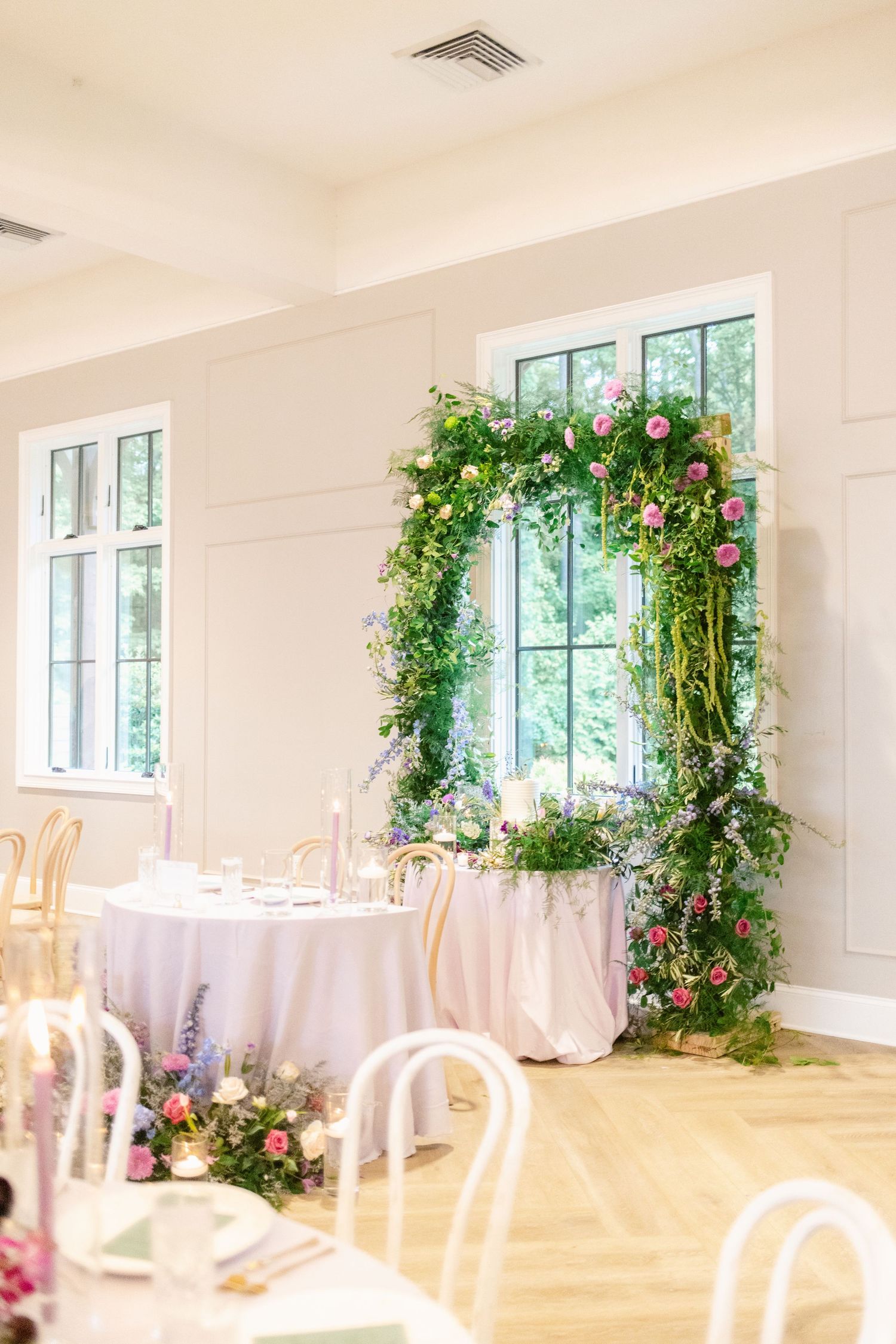 Wedding reception room with floral arch decorations and white tablecloths.