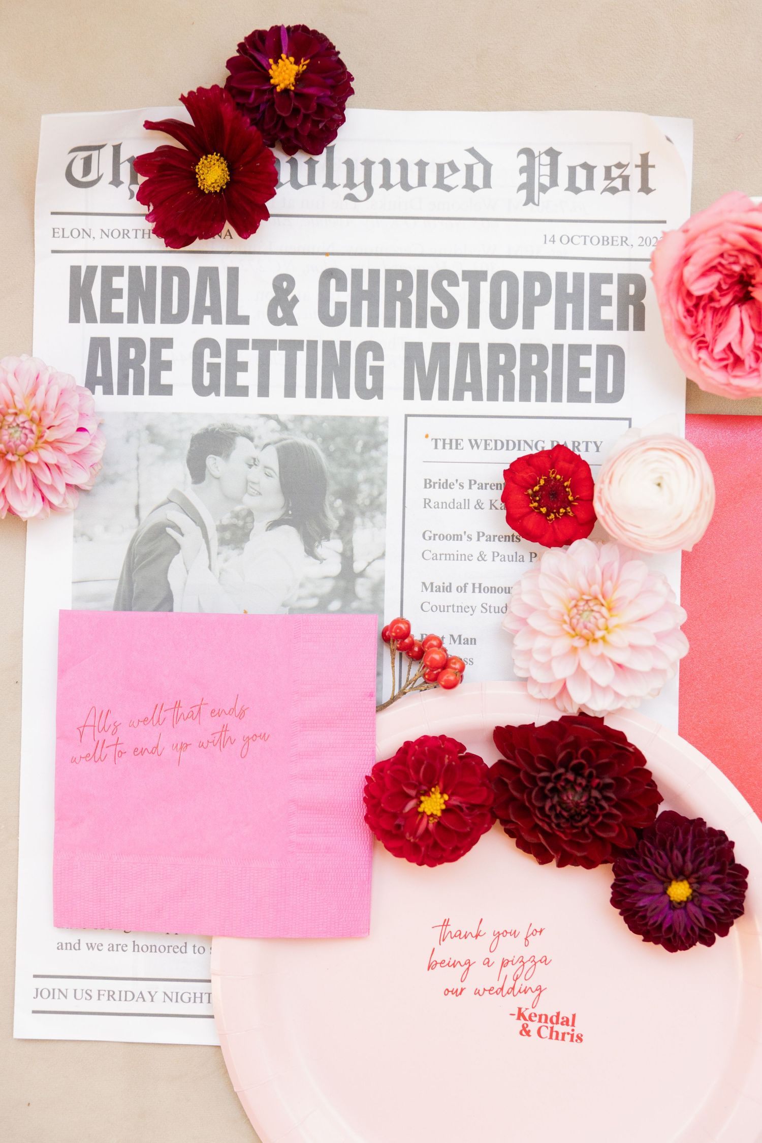 Wedding invitation details with burgundy and pink flowers arranged on a light pink background with newspaper style announcement.