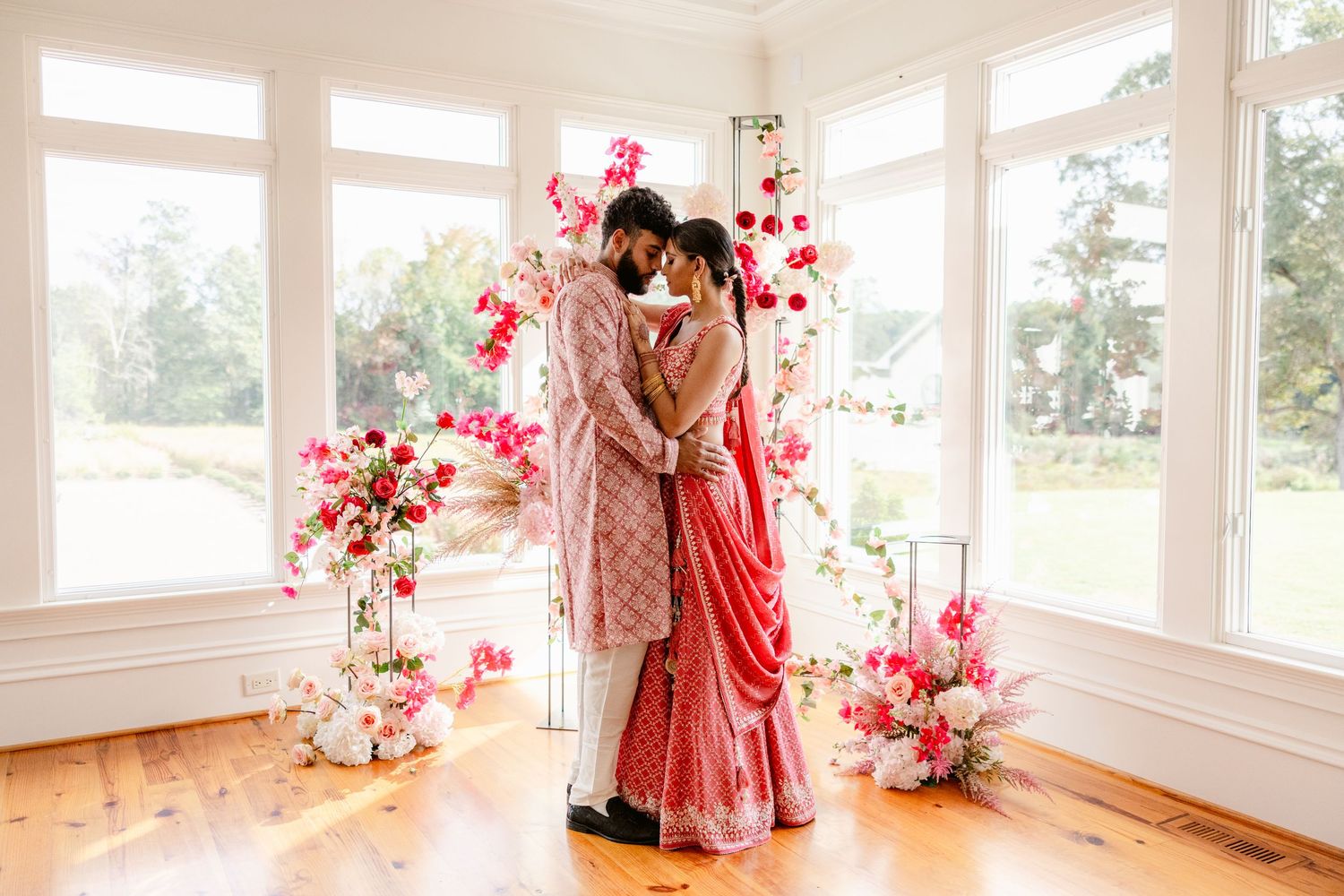 Bright sunlit room with pink floral decorations and large windows.