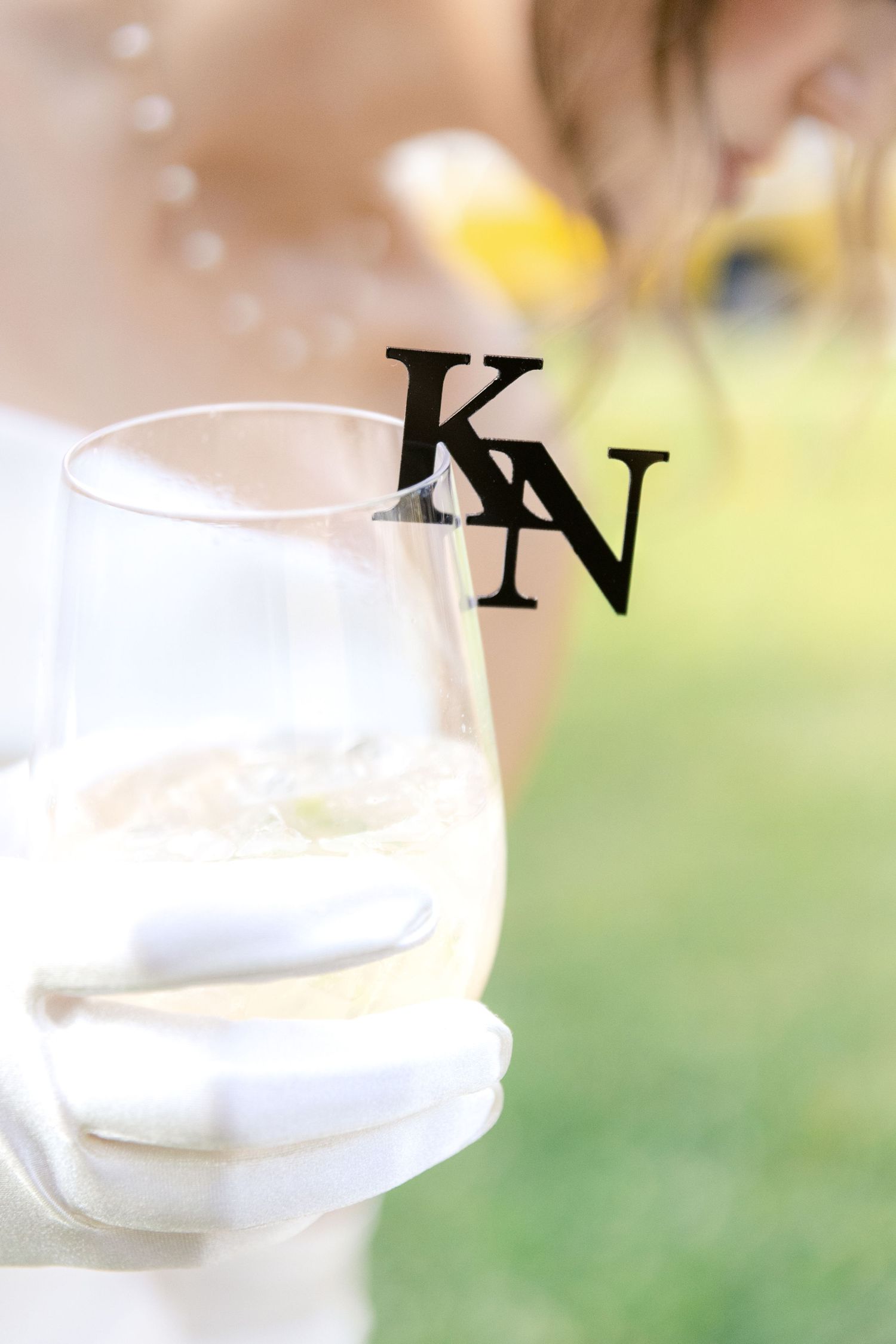 A wine glass decorated with 'KN' monogram against a soft blurred background.