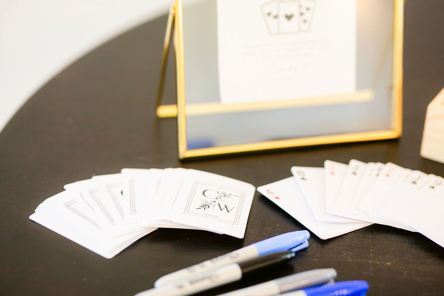 Playing cards spread out on dark table surface with pen and office supplies visible.