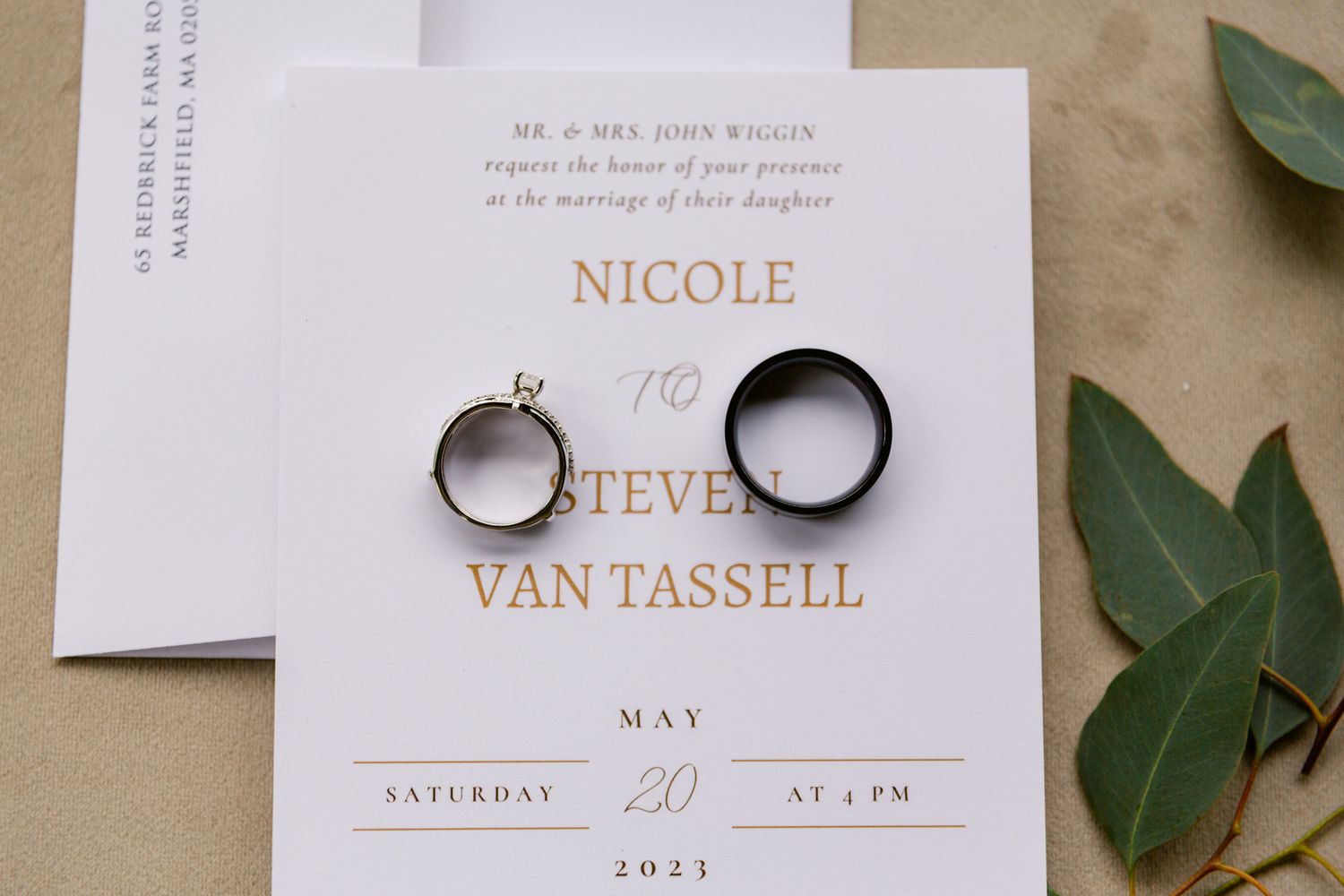 Elegant wedding invitation suite with white cards, floral elements, and gold details laid out on a neutral background.