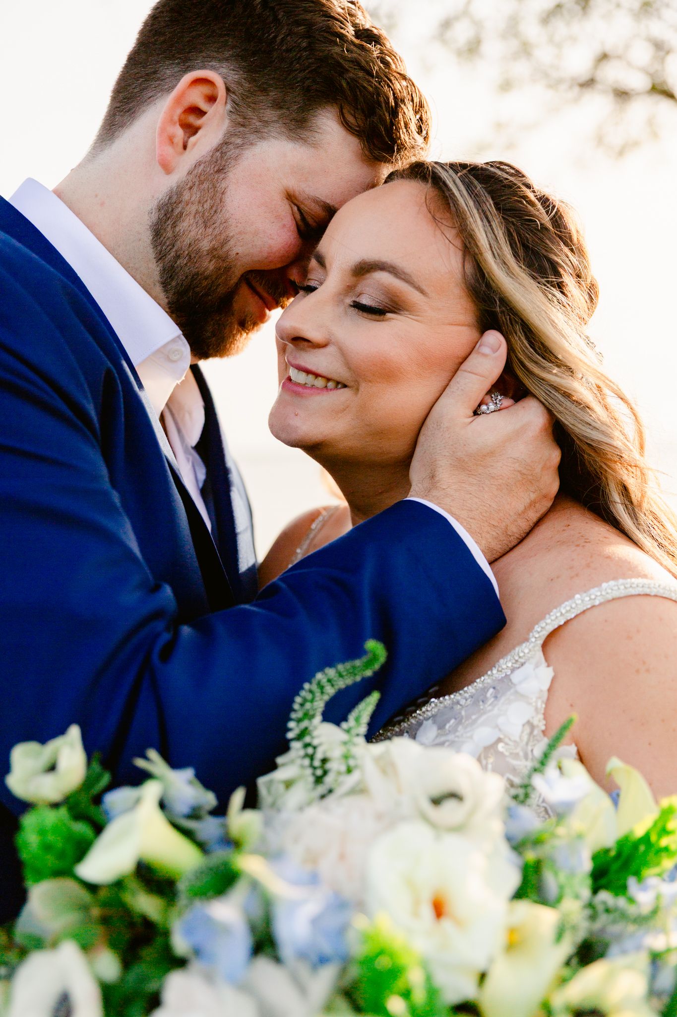 A romantic wedding moment captured in a series of close-up shots with white floral bouquets and greenery in the foreground.