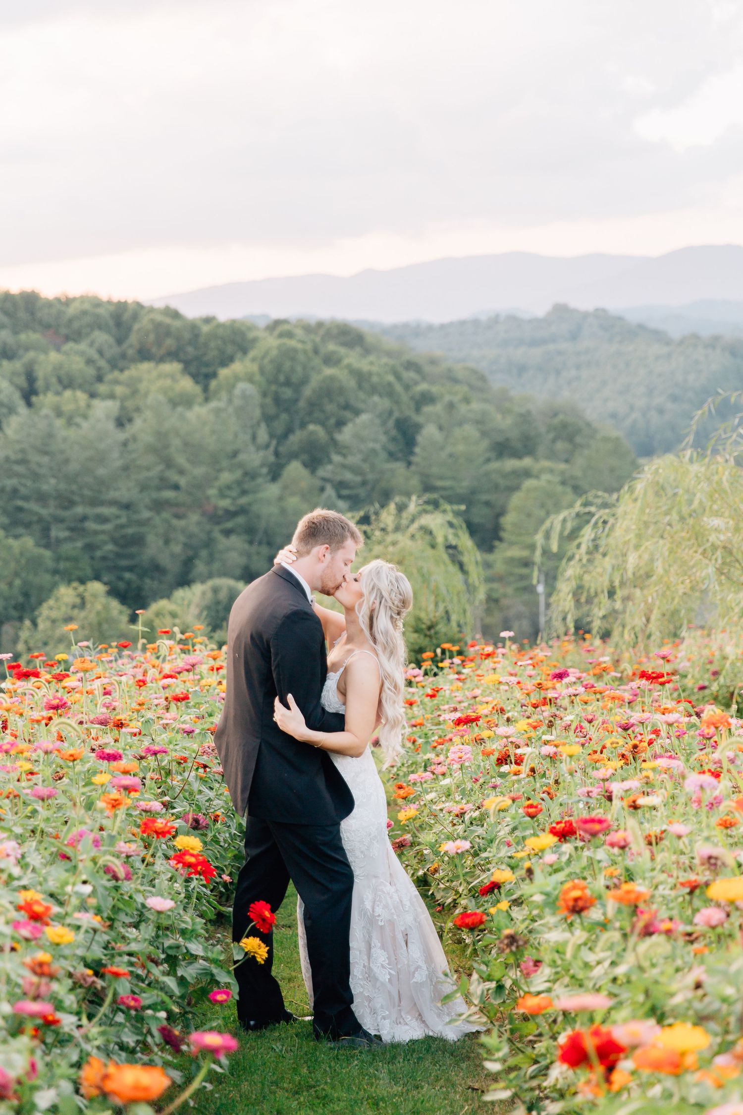 A couple shares a romantic moment in a vibrant field of orange and red poppies with rolling hills in the background.