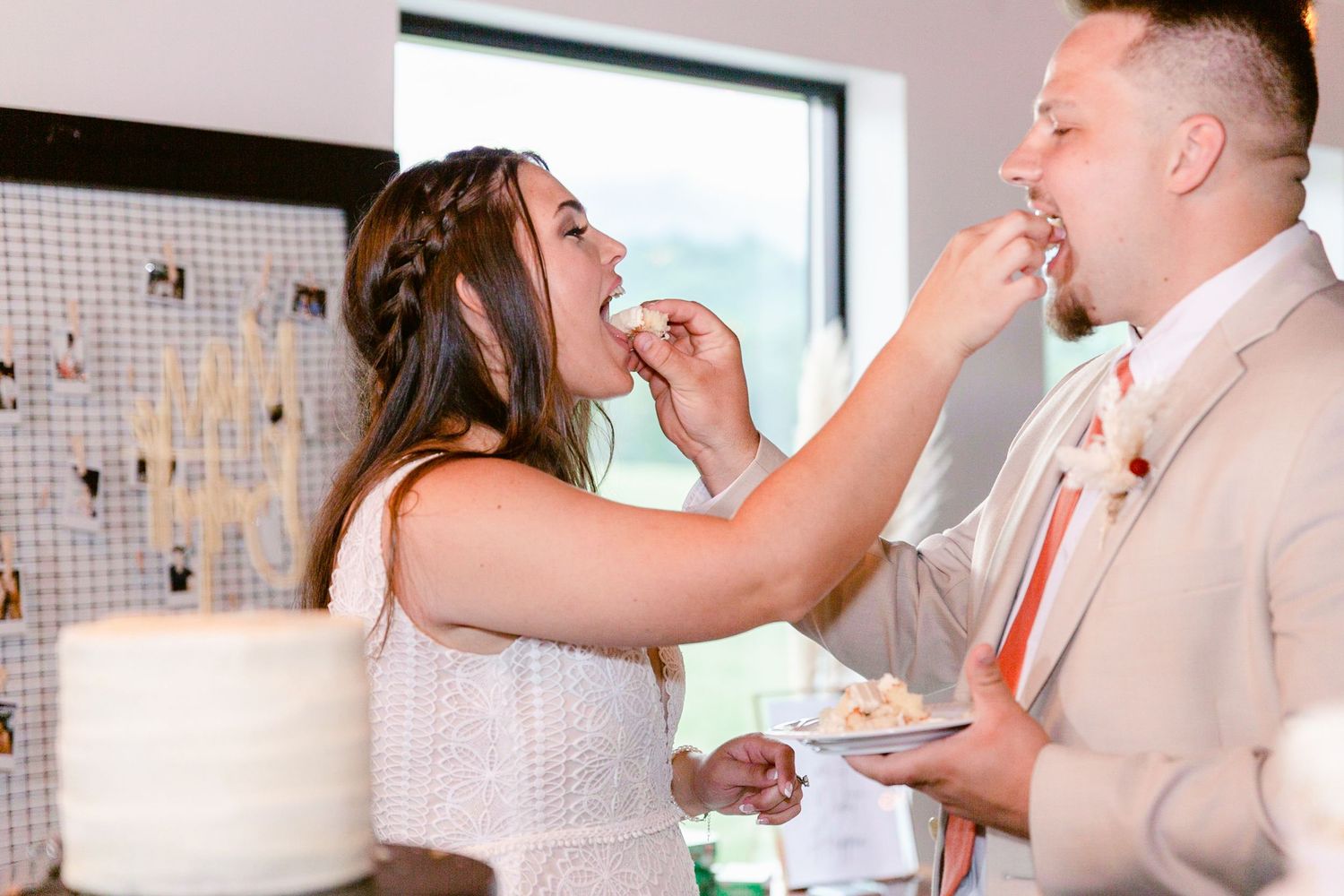 Wedding couple dancing in a bright reception space with white decor and natural lighting.