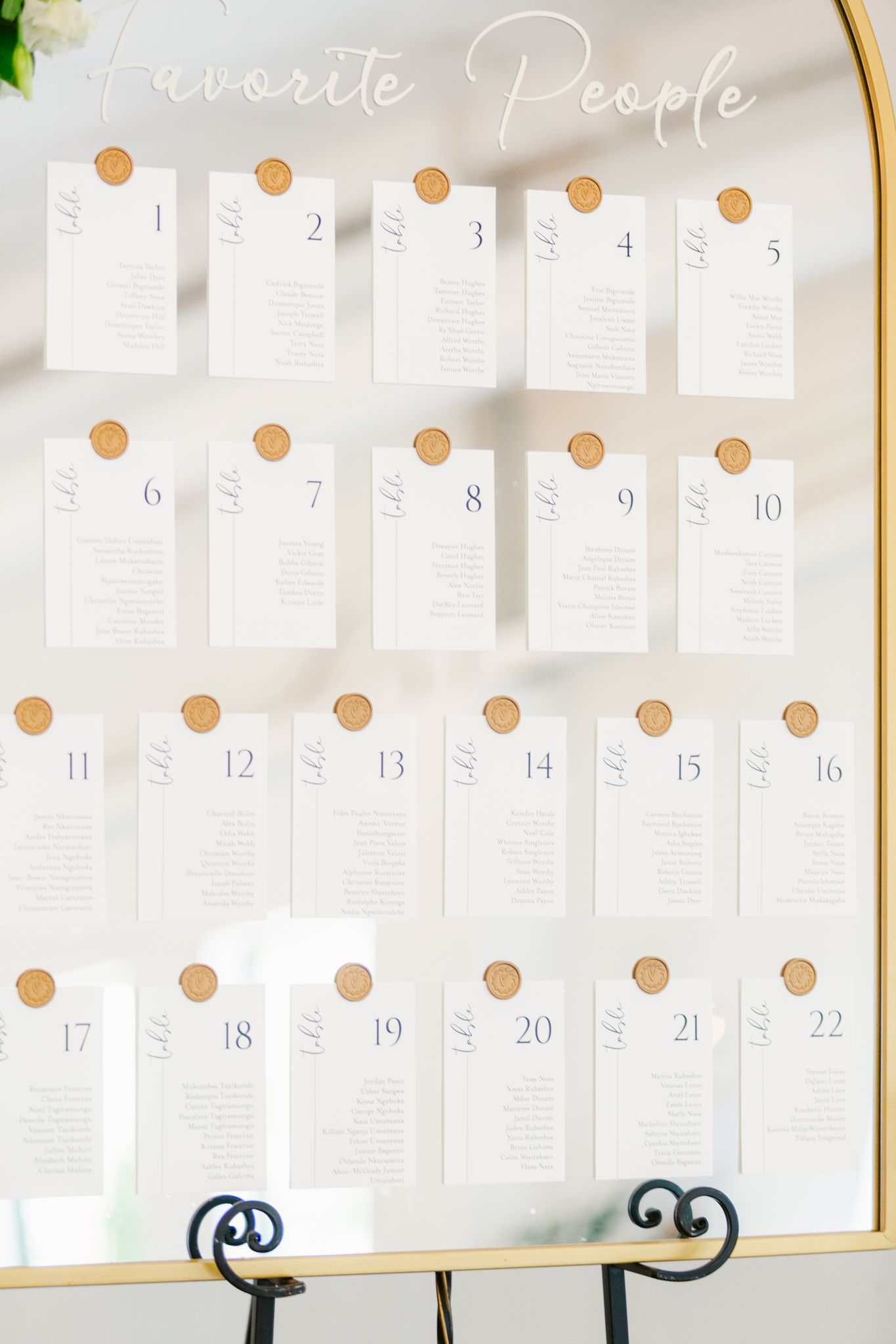Elegant wedding seating chart display with numbered cards arranged in rows on a white board with cursive header text.