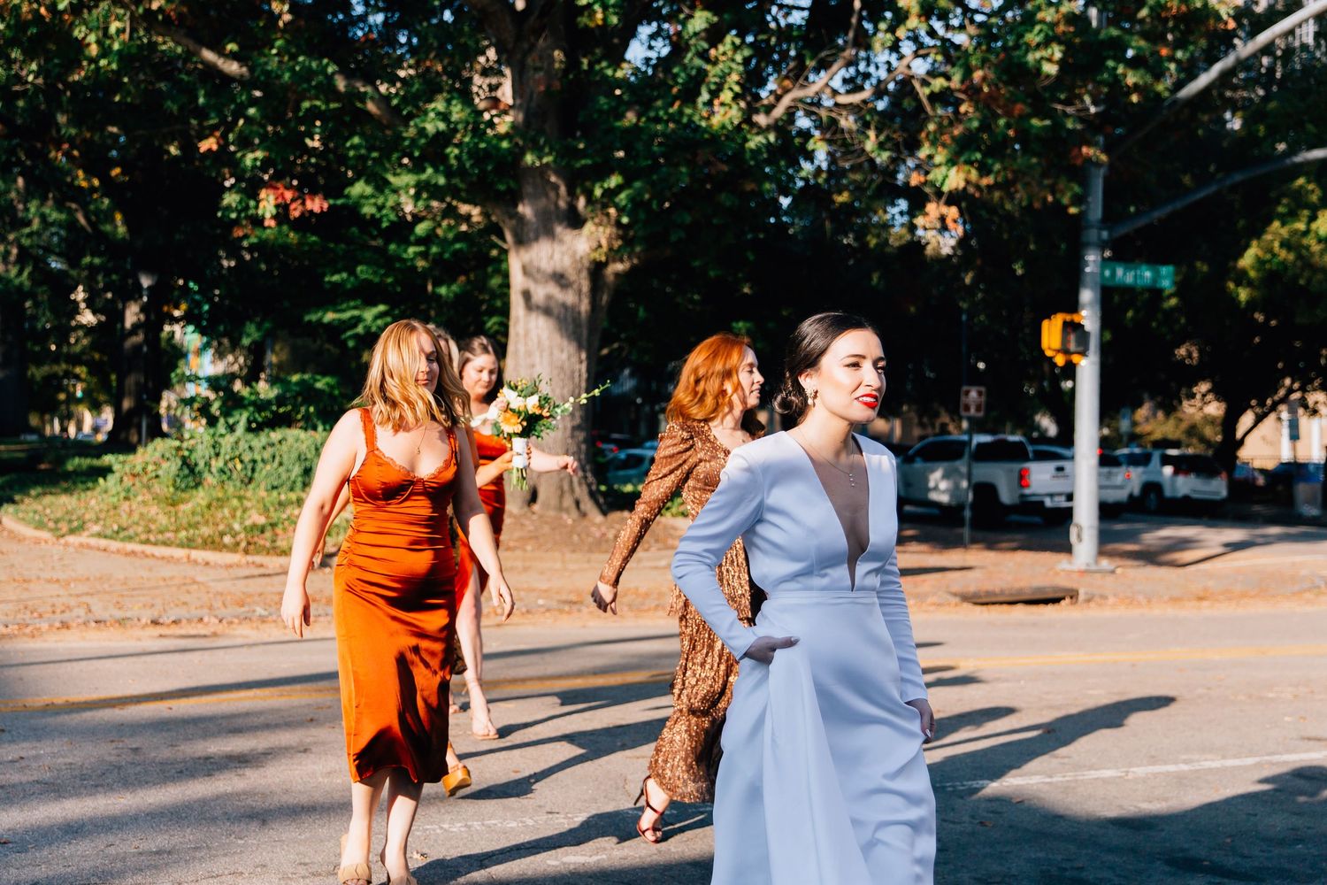People walking together on a sunny sidewalk path surrounded by lush green trees and foliage.