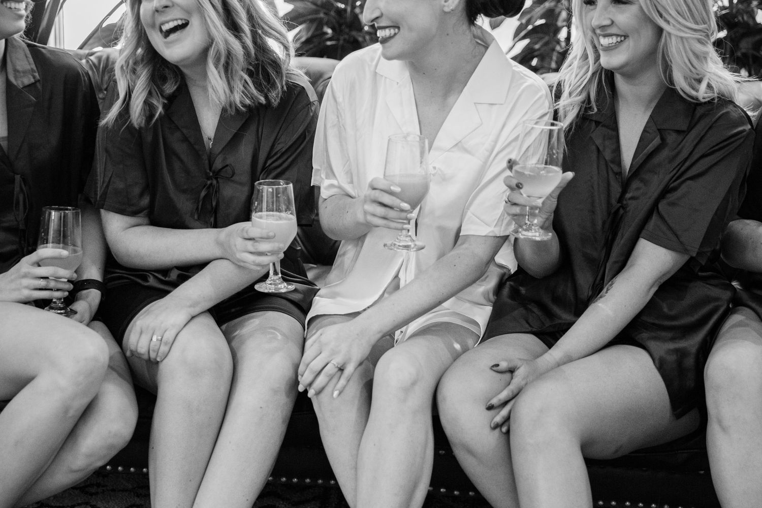 A group of people sitting together on steps share a candid laughing moment in black and white.