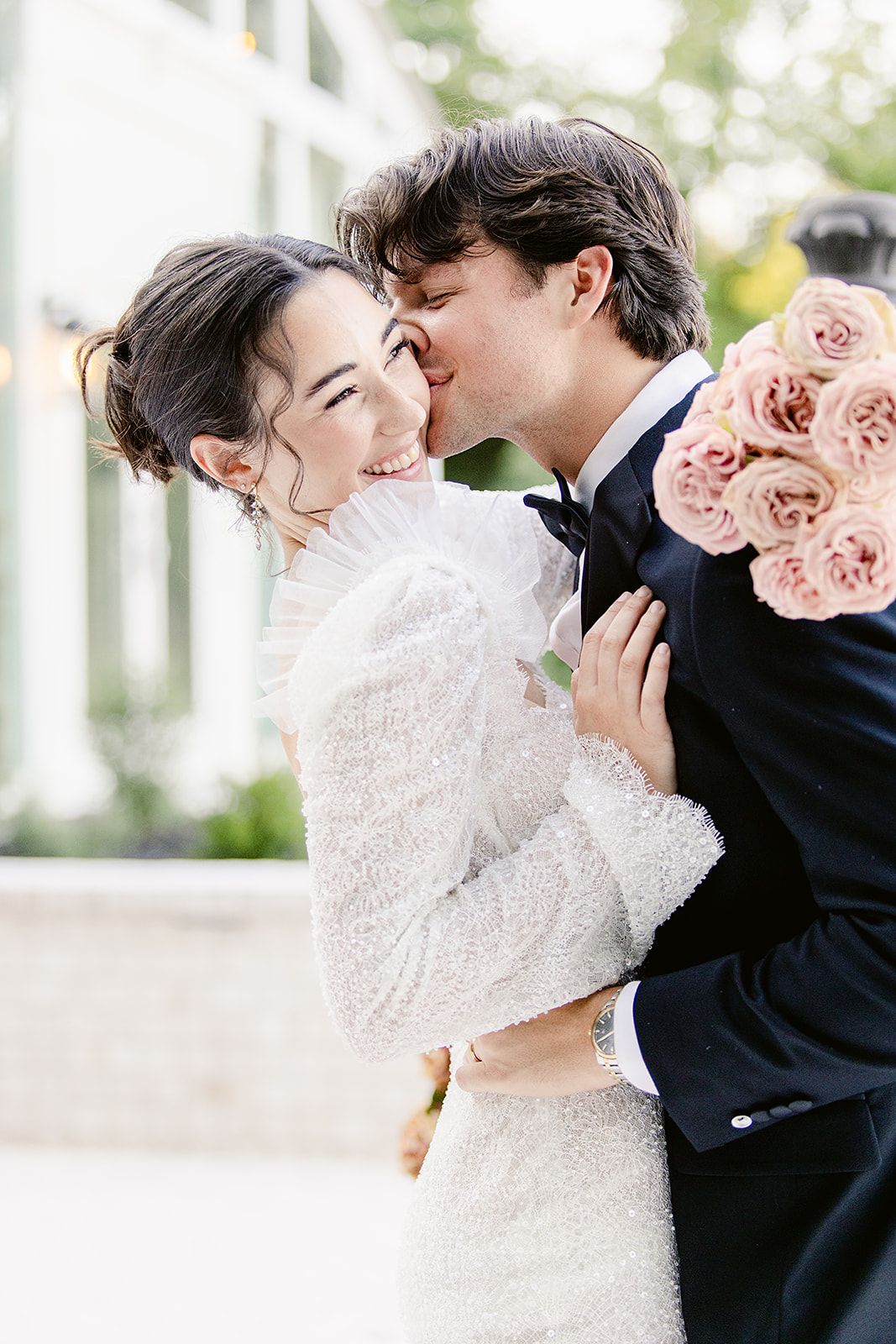 A tender moment between newlyweds as they share an intimate embrace with pink roses in hand.