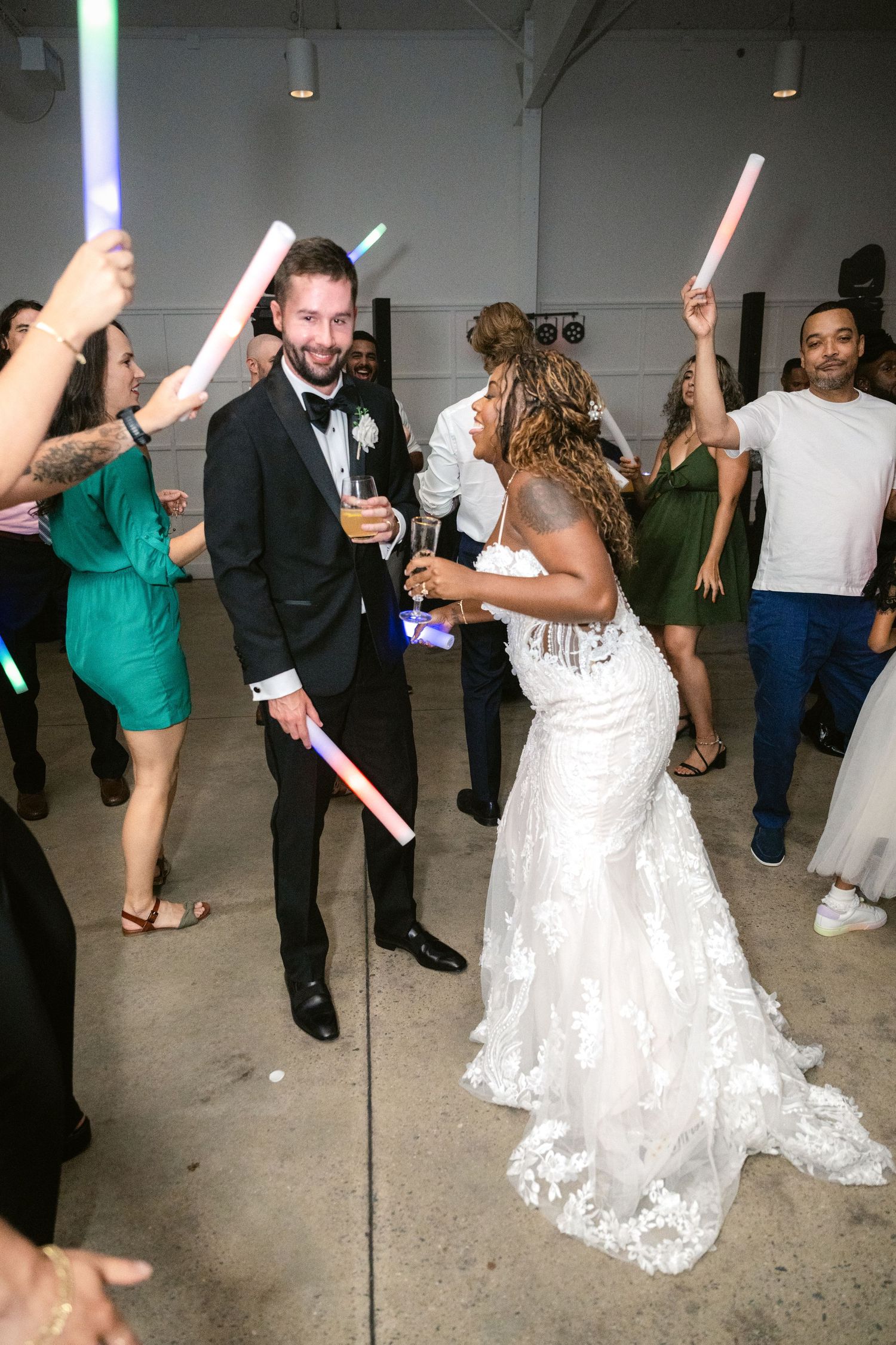 Wedding guests dancing with light-up foam sticks on the dance floor.