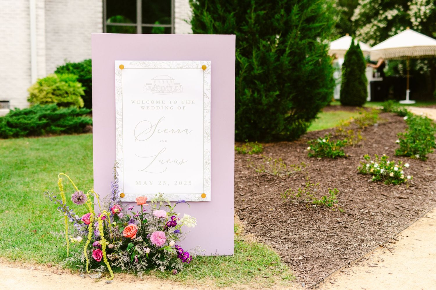 Garden wedding signage and floral decorations against white walls.