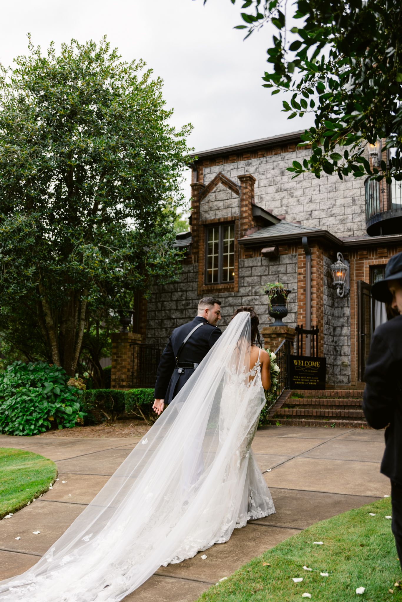 A romantic wedding photo showing a long white dress train flowing across a stone courtyard at an elegant stone venue.