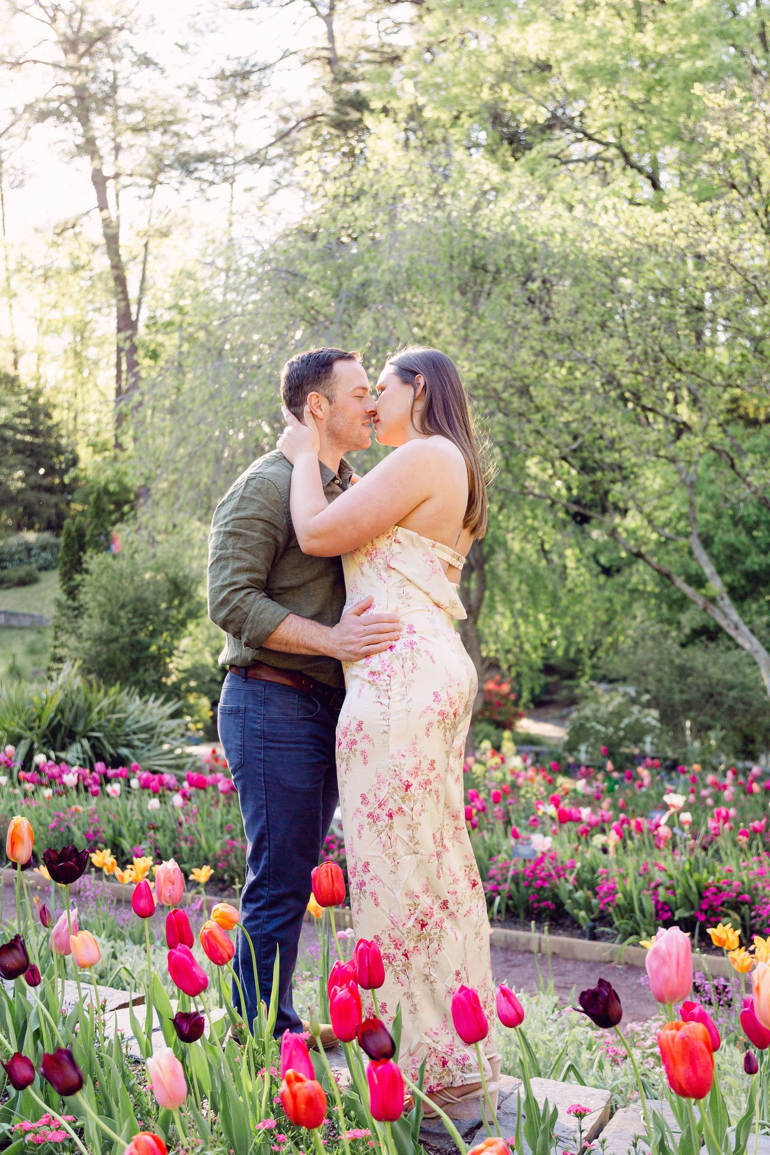 A romantic moment captured in a vibrant spring garden filled with blooming pink and red tulips.