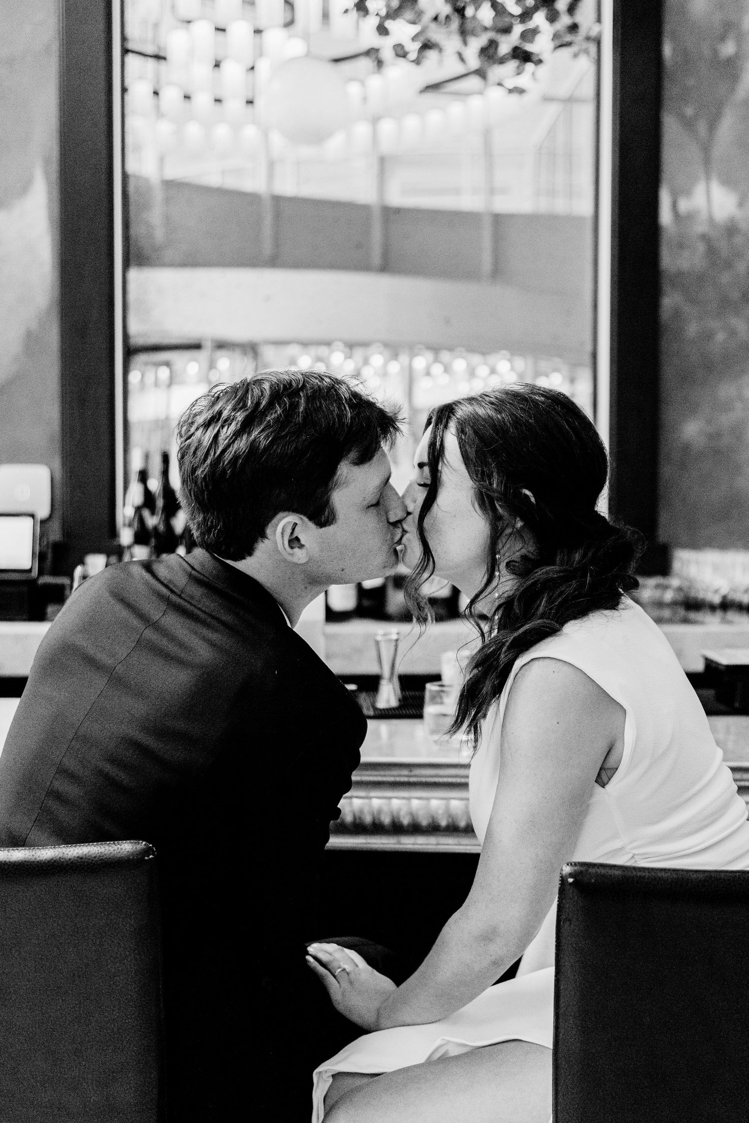 A black and white photo series showing couples kissing at a bar counter.