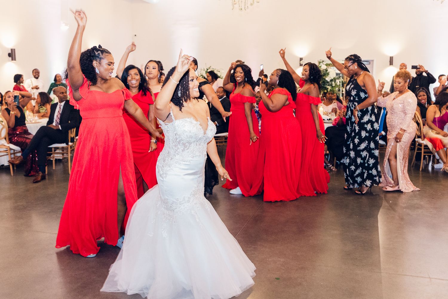 Wedding celebration with bridesmaids in red dresses dancing alongside the bride in white.