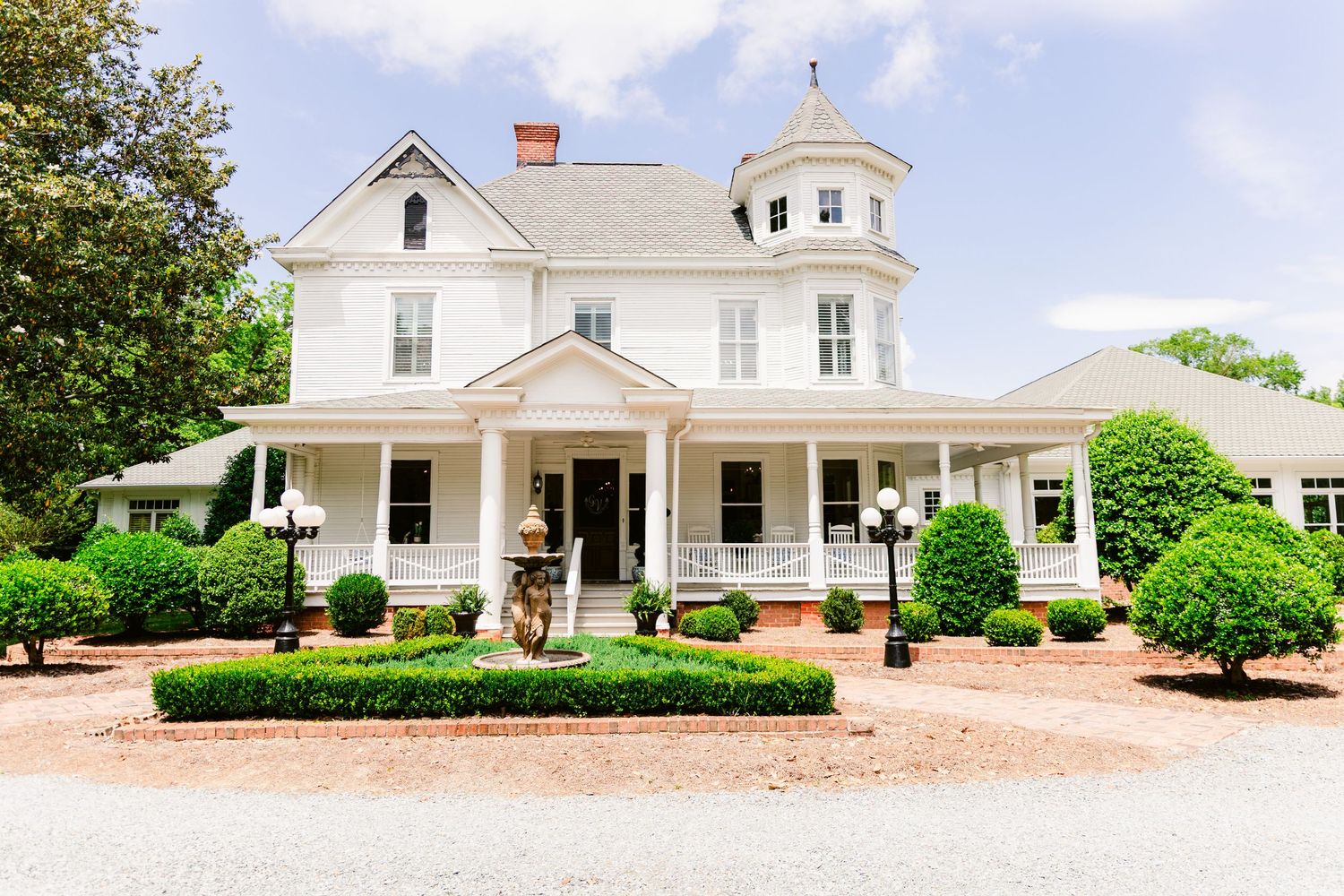 White farmhouse-style building with wraparound porch and cupola shown from multiple angles in panoramic view.